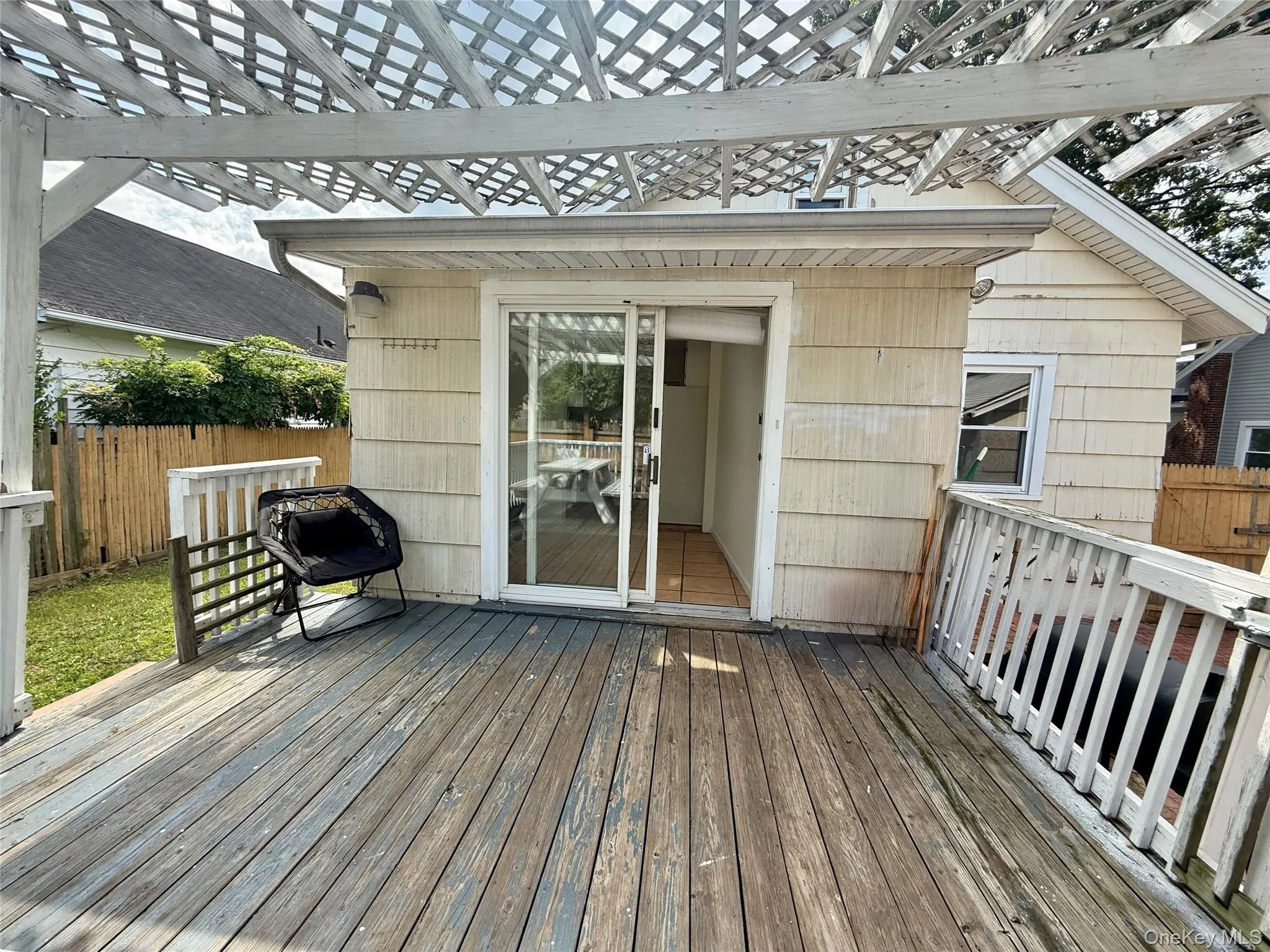 Expansive outdoor deck featuring wood-finish flooring, a white lattice pergola, and white railing Expansive outdoor deck featuring wood-finish flooring, a white lattice pergola, and white railing