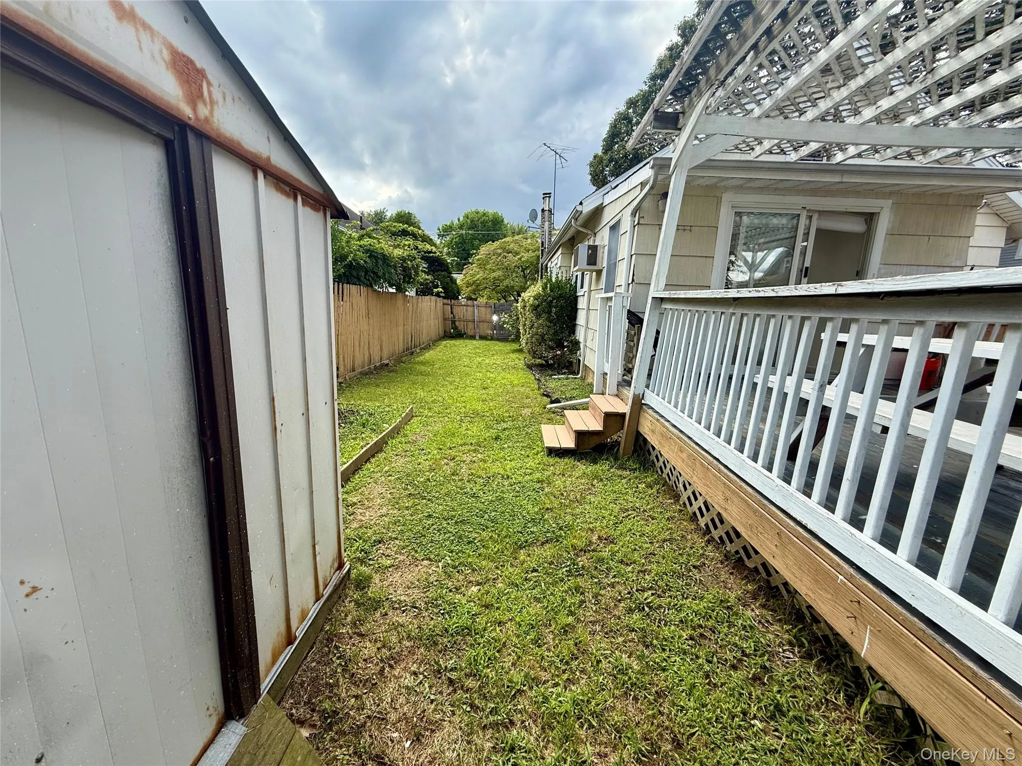 Expansive grass area featuring a detached storage shed, privacy fencing, and a full-length deck with a lattice privacy skirt Expansive grass area featuring a detached storage shed, privacy fencing, and a full-length deck with a lattice privacy skirt