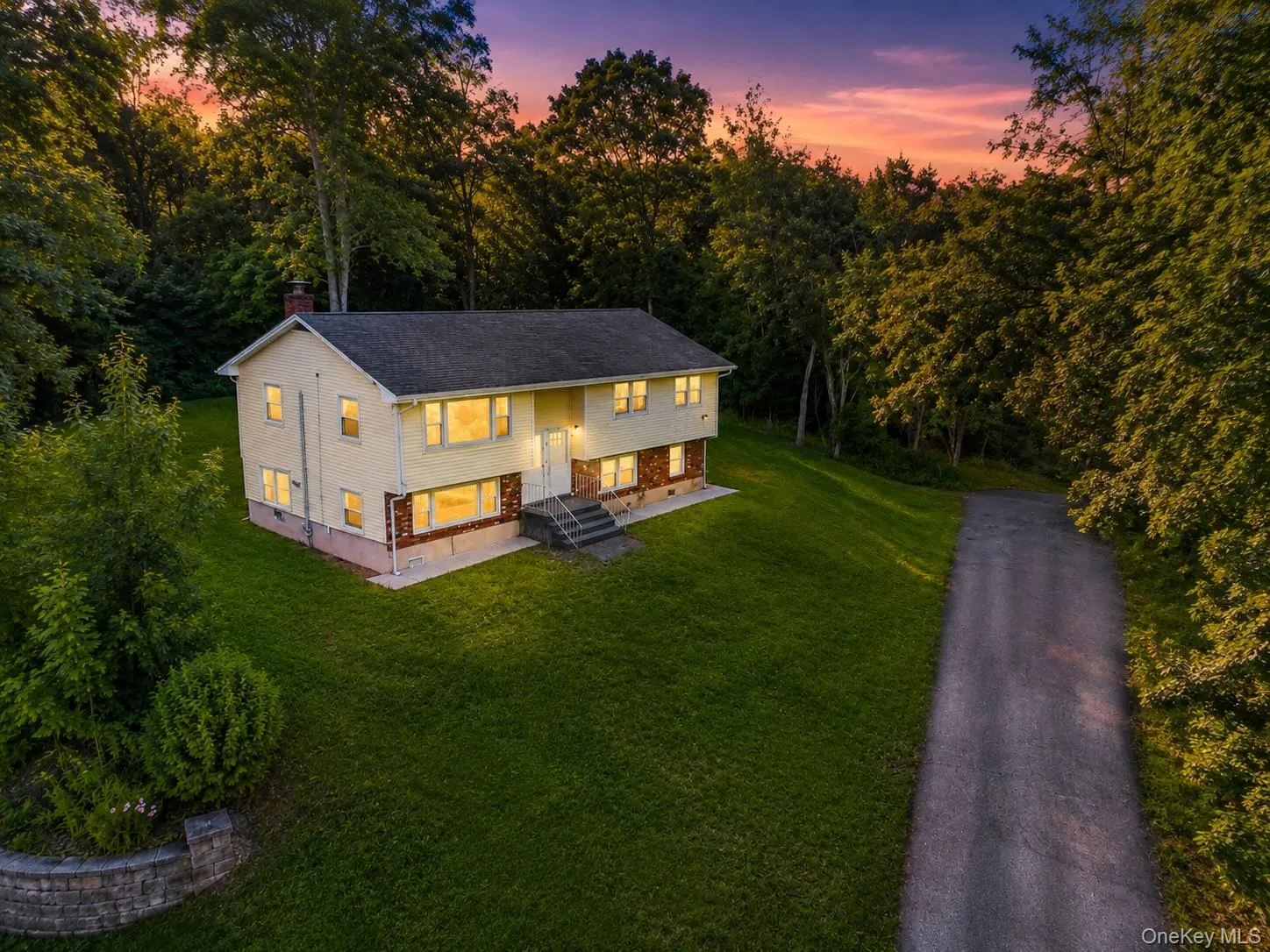 Split-level residence featuring a light-colored siding exterior with a dark-shingled roof Split-level residence featuring a light-colored siding exterior with a dark-shingled roof