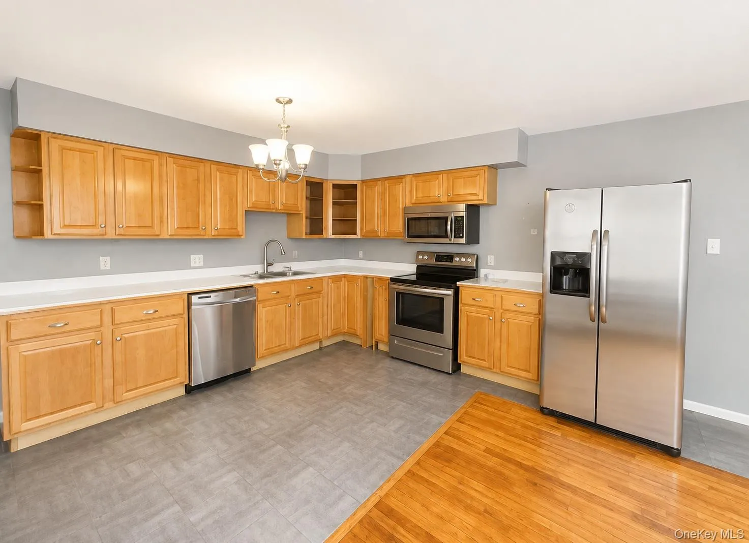 Kitchen featuring extensive light wood cabinetry, white countertops, stainless steel appliances, and a gray tile-patterned floor Kitchen featuring extensive light wood cabinetry, white countertops, stainless steel appliances, and a gray tile-patterned floor