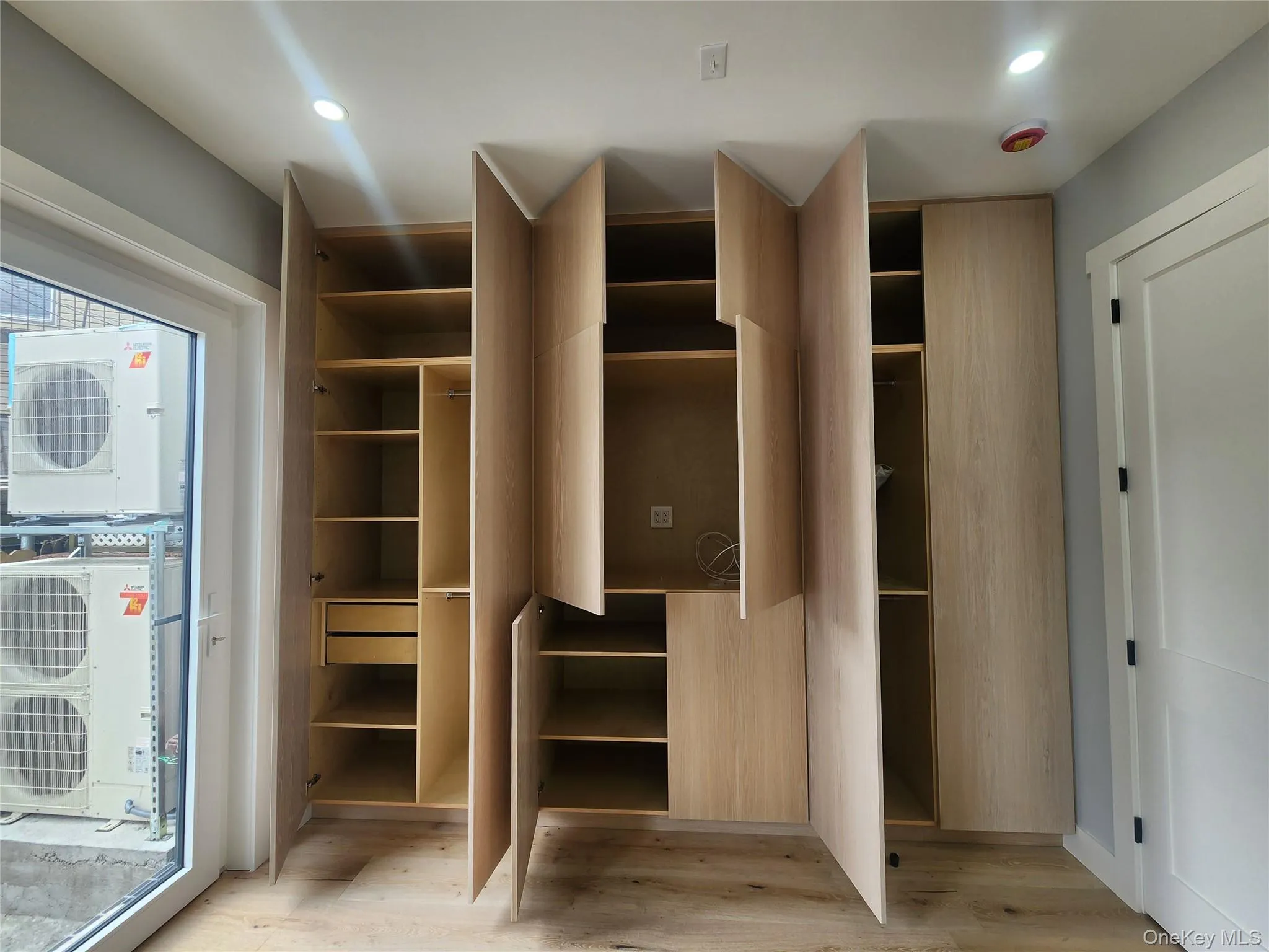 Built-in wardrobe system featuring light wood-finish cabinetry, integrated shelving, and soft-close drawers Built-in wardrobe system featuring light wood-finish cabinetry, integrated shelving, and soft-close drawers