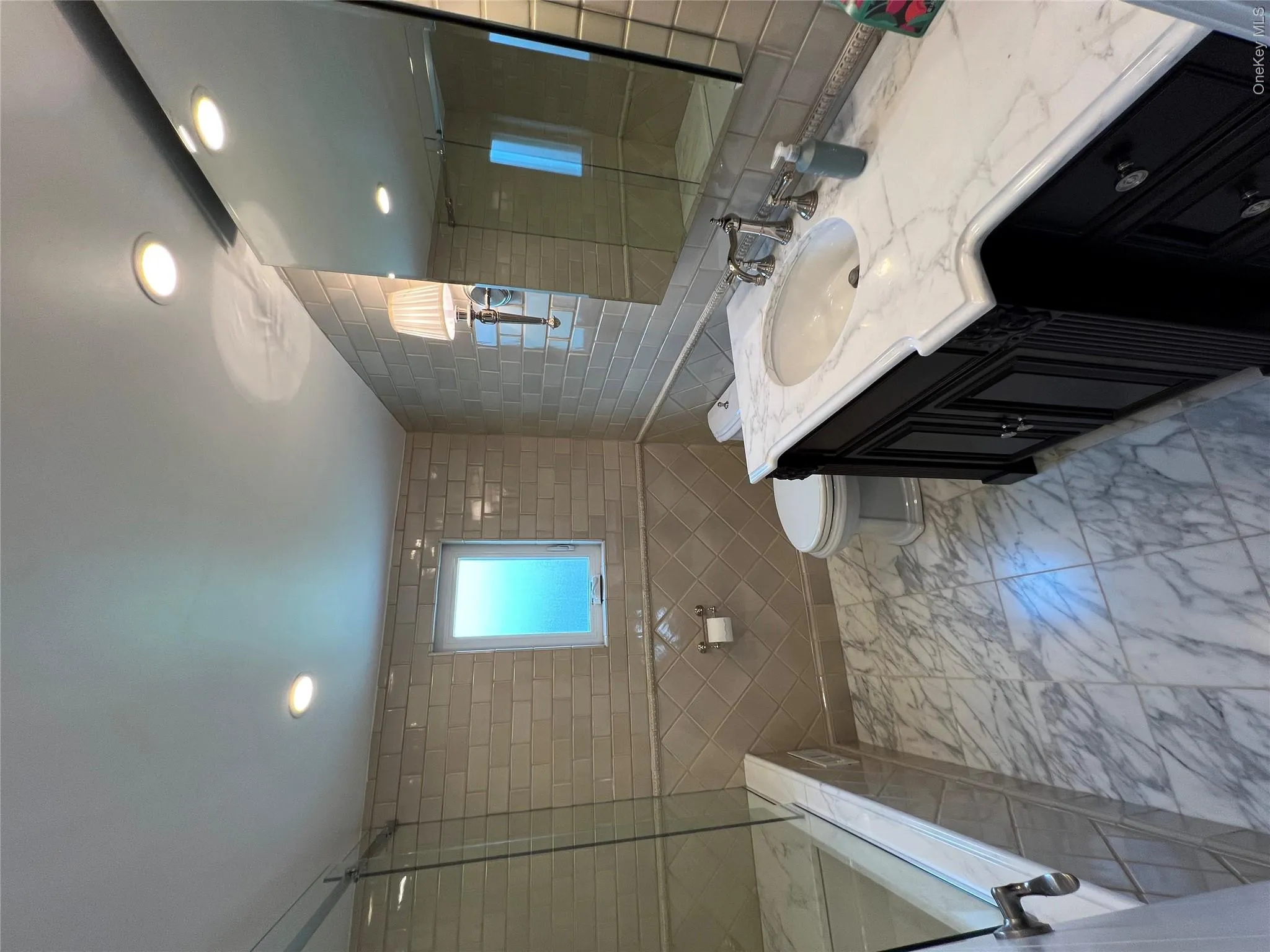 Spa-inspired primary bathroom featuring a walk-in shower with subway tile surround, marble-finish flooring, and a double vanity with quartz countertop, vessel sink, and polished chrome fixtures Spa-inspired primary bathroom featuring a walk-in shower with subway tile surround, marble-finish flooring, and a double vanity with quartz countertop, vessel sink, and polished chrome fixtures