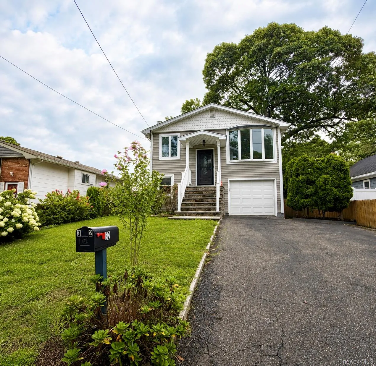 Exterior featuring gray siding, a covered entry porch, a bay window, and an attached garage with a white door. Exterior featuring gray siding, a covered entry porch, a bay window, and an attached garage with a white door.