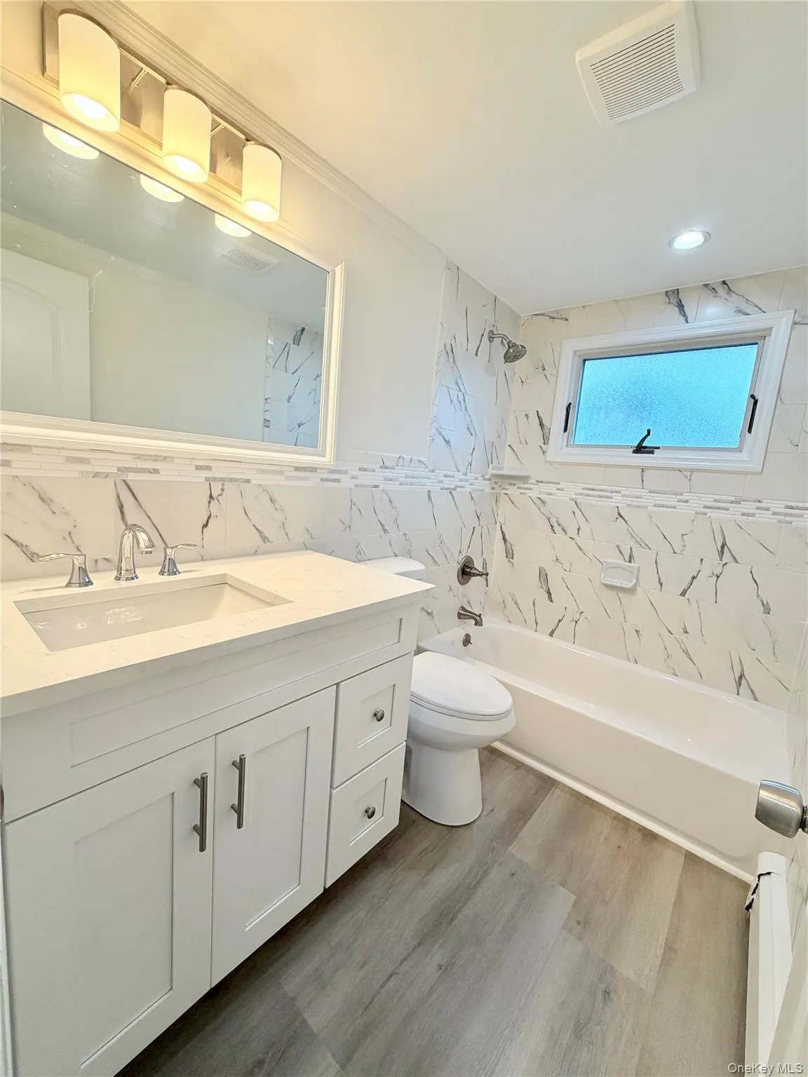 Bathroom featuring a single vanity with stone-finish countertop and built-in bathtub. Bathroom featuring a single vanity with stone-finish countertop and built-in bathtub.