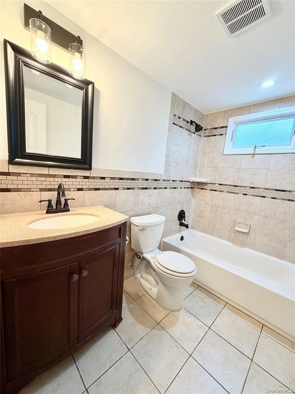 Bathroom featuring a single vanity with stone-finish countertop and built-in bathtub. Bathroom featuring a single vanity with stone-finish countertop and built-in bathtub.