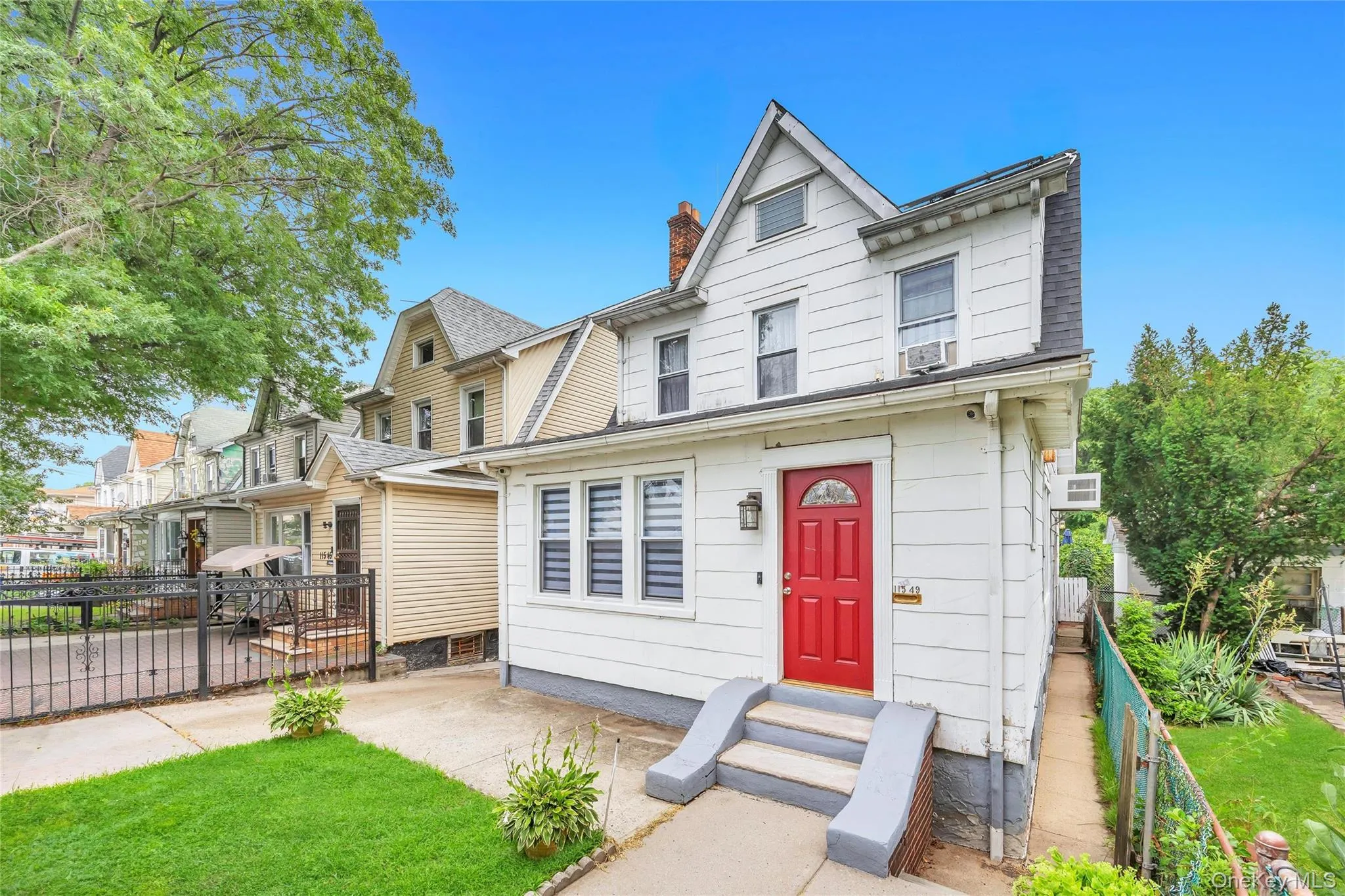 White siding exterior with a bright red front door, featuring a gabled roofline and window shutters White siding exterior with a bright red front door, featuring a gabled roofline and window shutters