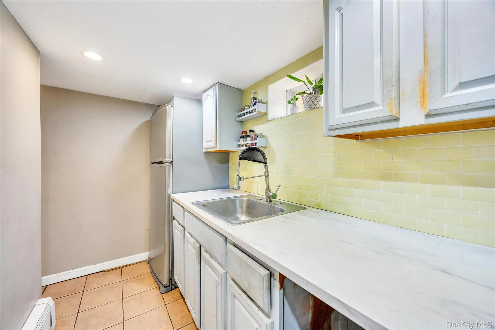Compact kitchen area featuring a stainless steel sink, a pull-down faucet, and a subway tile backsplash Compact kitchen area featuring a stainless steel sink, a pull-down faucet, and a subway tile backsplash