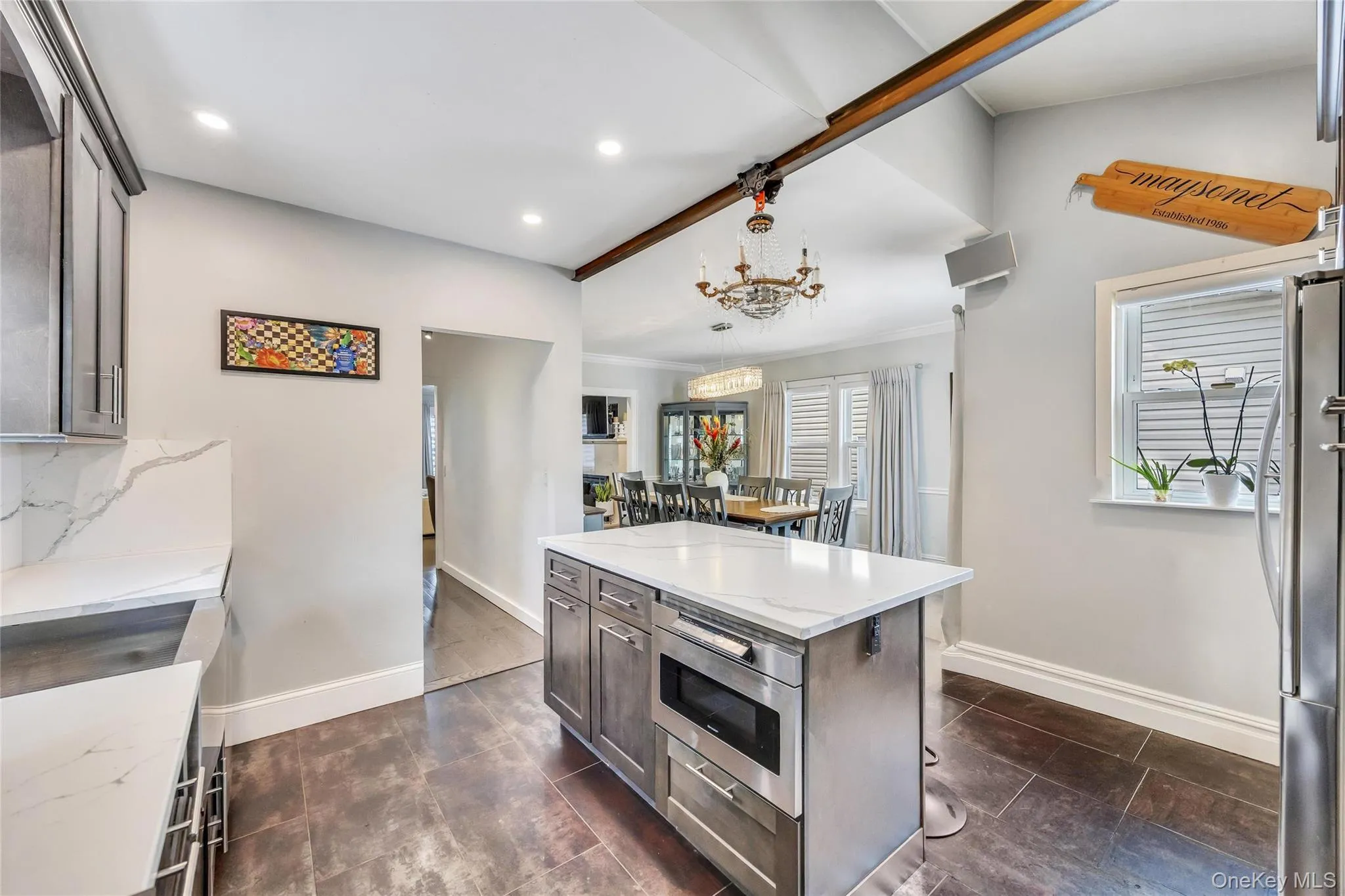 Kitchen featuring a central island with integrated microwave, white countertop, and dark wood-finish cabinetry Kitchen featuring a central island with integrated microwave, white countertop, and dark wood-finish cabinetry