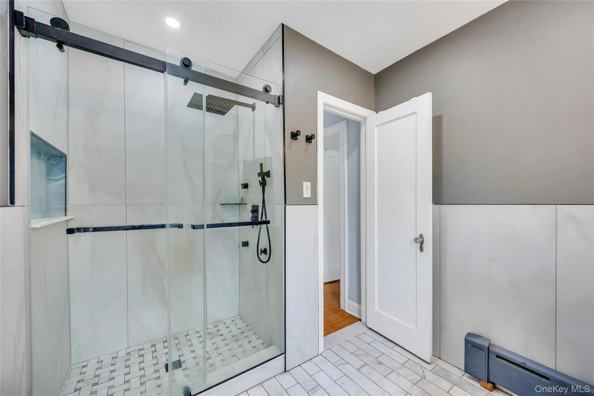 Walk-in shower featuring a sliding glass door, rainfall showerhead, and matte black fixtures Walk-in shower featuring a sliding glass door, rainfall showerhead, and matte black fixtures