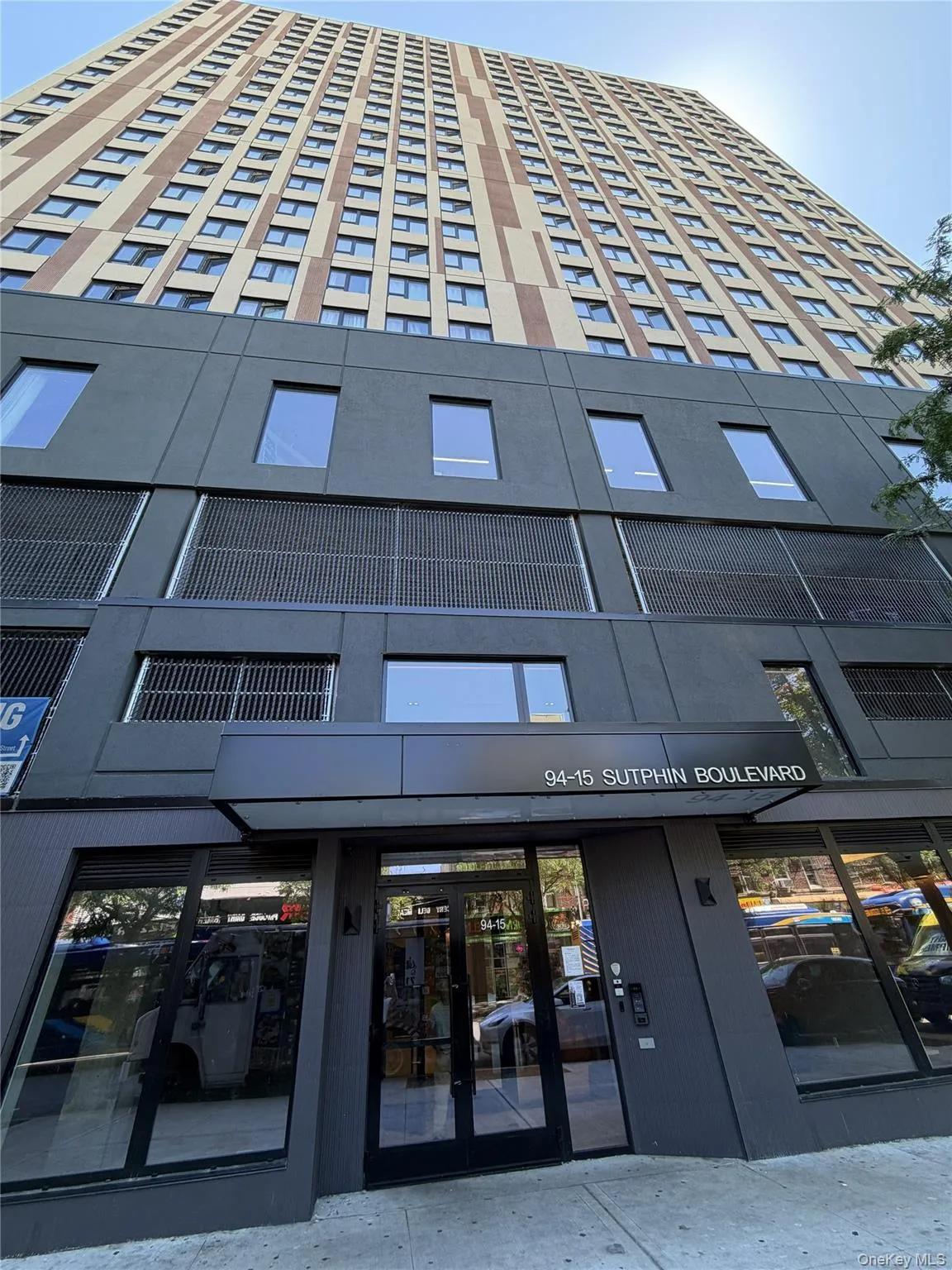 Contemporary high-rise building featuring a multi-story base with dark paneling and large storefront windows Contemporary high-rise building featuring a multi-story base with dark paneling and large storefront windows
