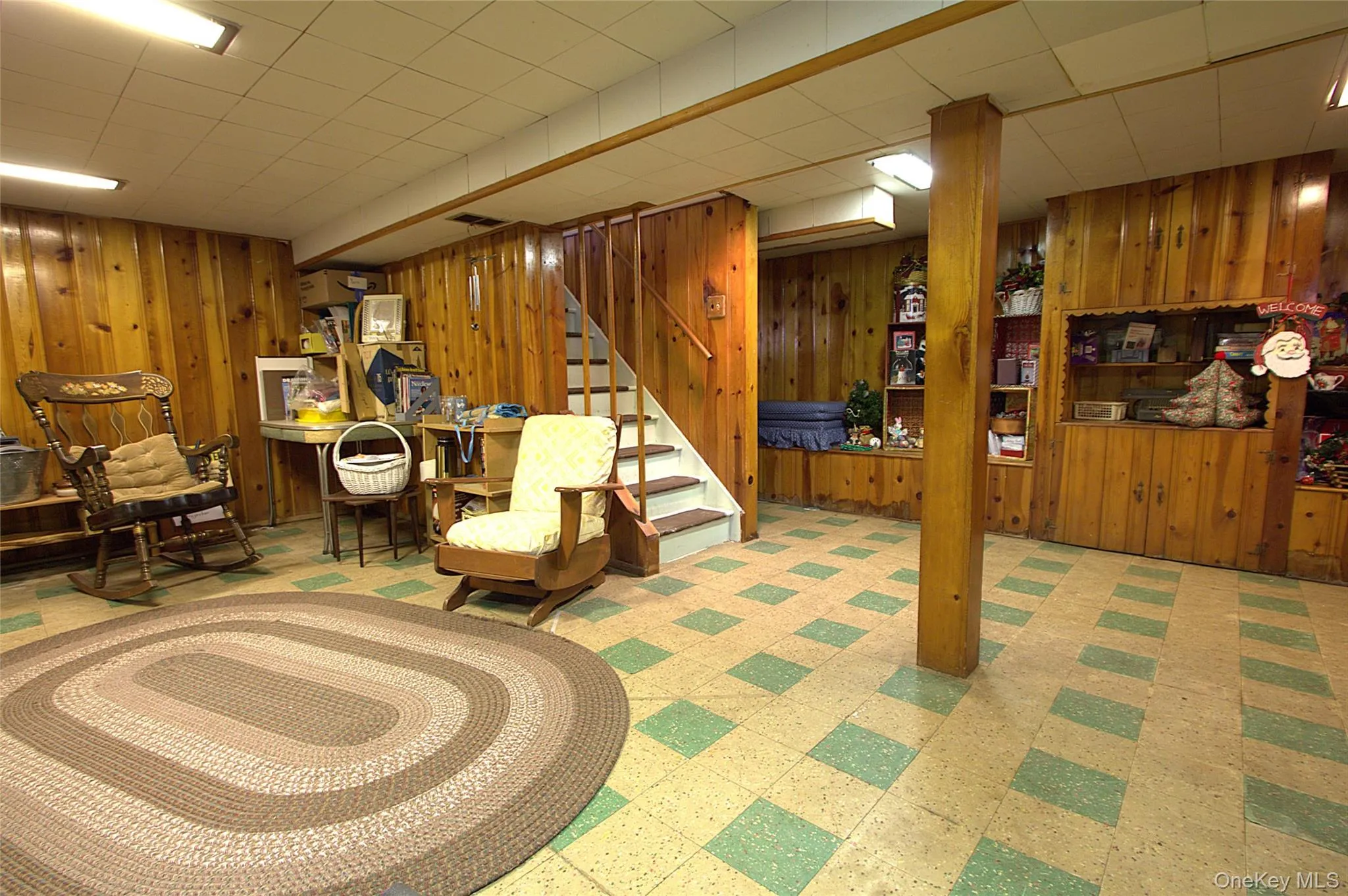 Wood paneling throughout, built-in shelving, staircase with wood railing, recessed panel ceiling, and patterned flooring Wood paneling throughout, built-in shelving, staircase with wood railing, recessed panel ceiling, and patterned flooring