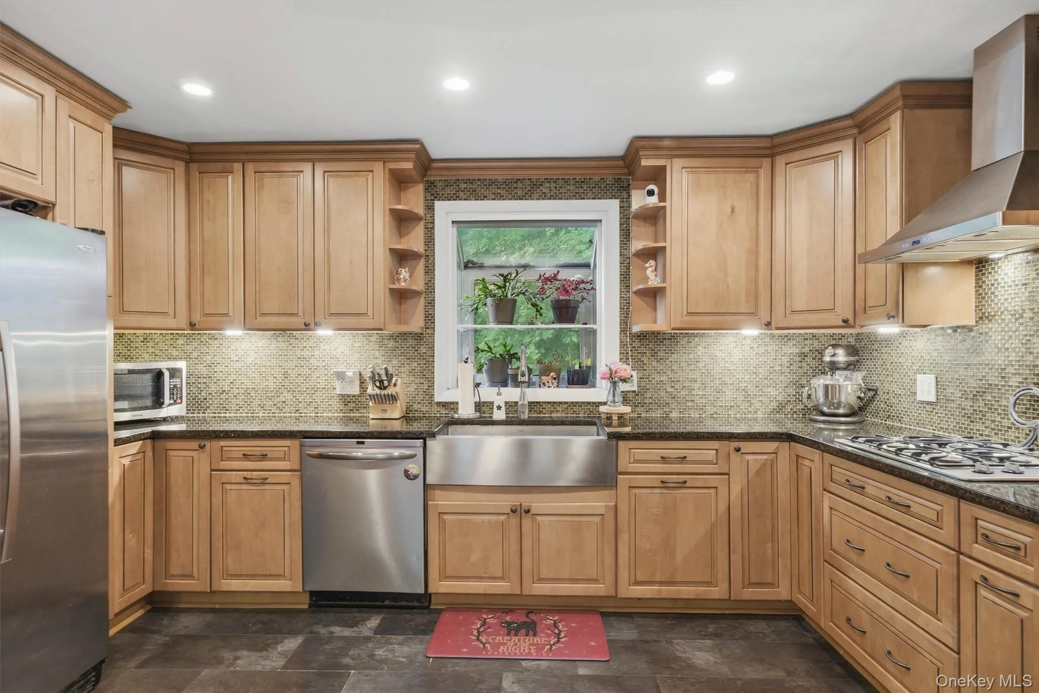 Eat in kitchen featuring custom countertops, a tile backsplash and stainless steel appliances including a gas range and stainless steel farmhouse sink Eat in kitchen featuring custom countertops, a tile backsplash and stainless steel appliances including a gas range and stainless steel farmhouse sink