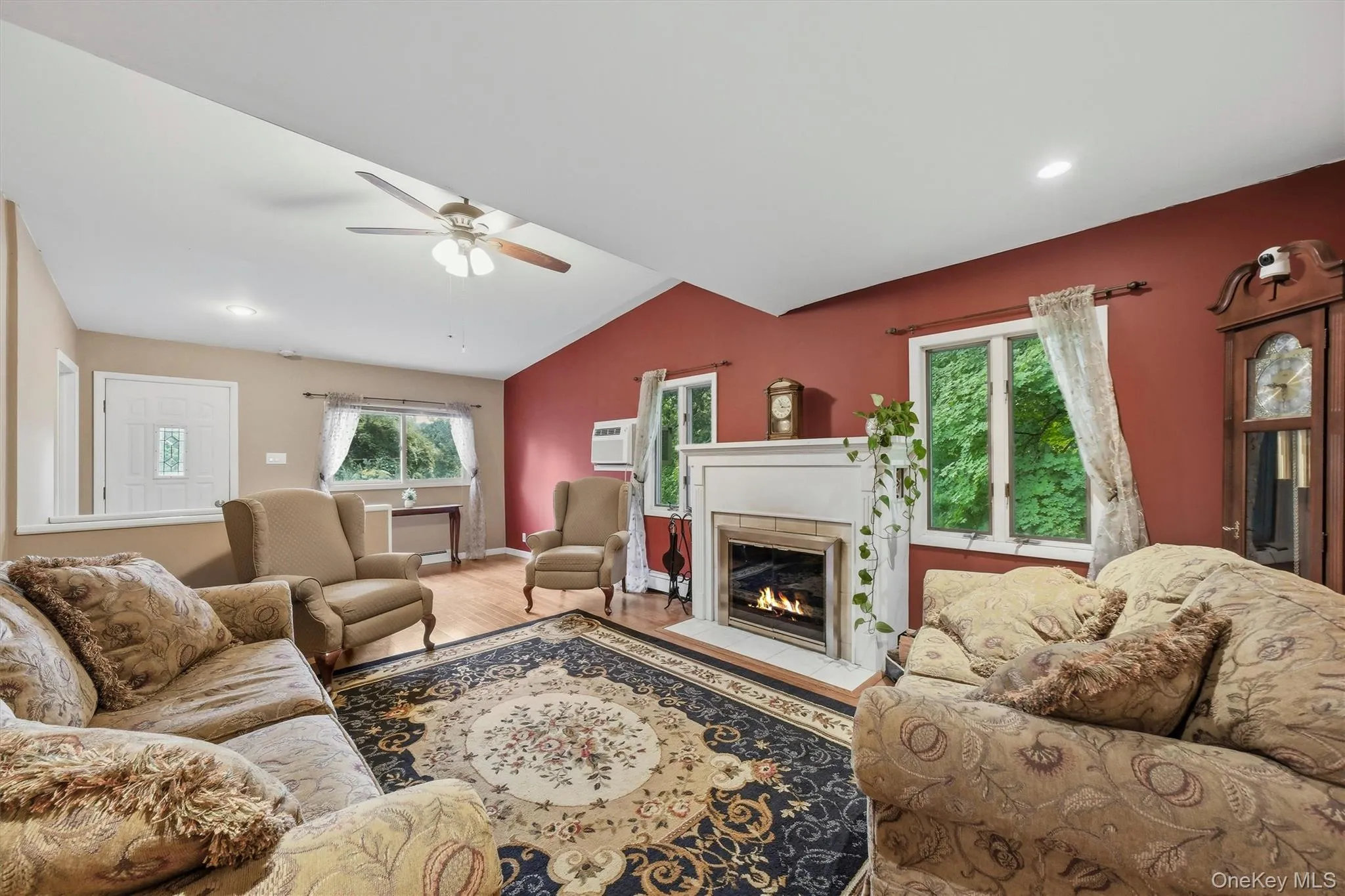 Living room featuring a wood burning fireplace with a classic mantel, hardwood floors, recessed lighting, and multiple windows Living room featuring a wood burning fireplace with a classic mantel, hardwood floors, recessed lighting, and multiple windows