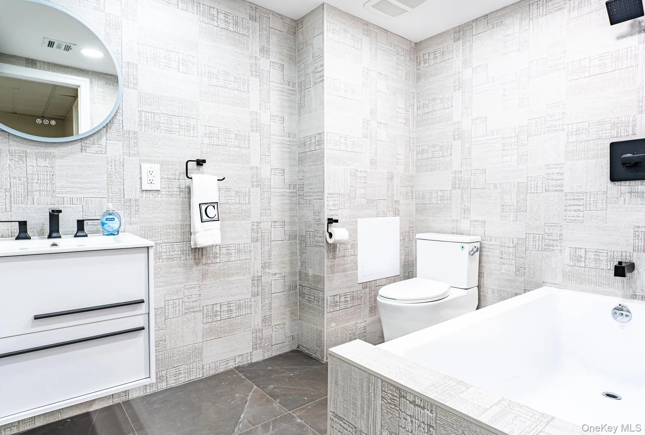 Modern bathroom featuring full-height patterned wall tiling and dark tile flooring Modern bathroom featuring full-height patterned wall tiling and dark tile flooring