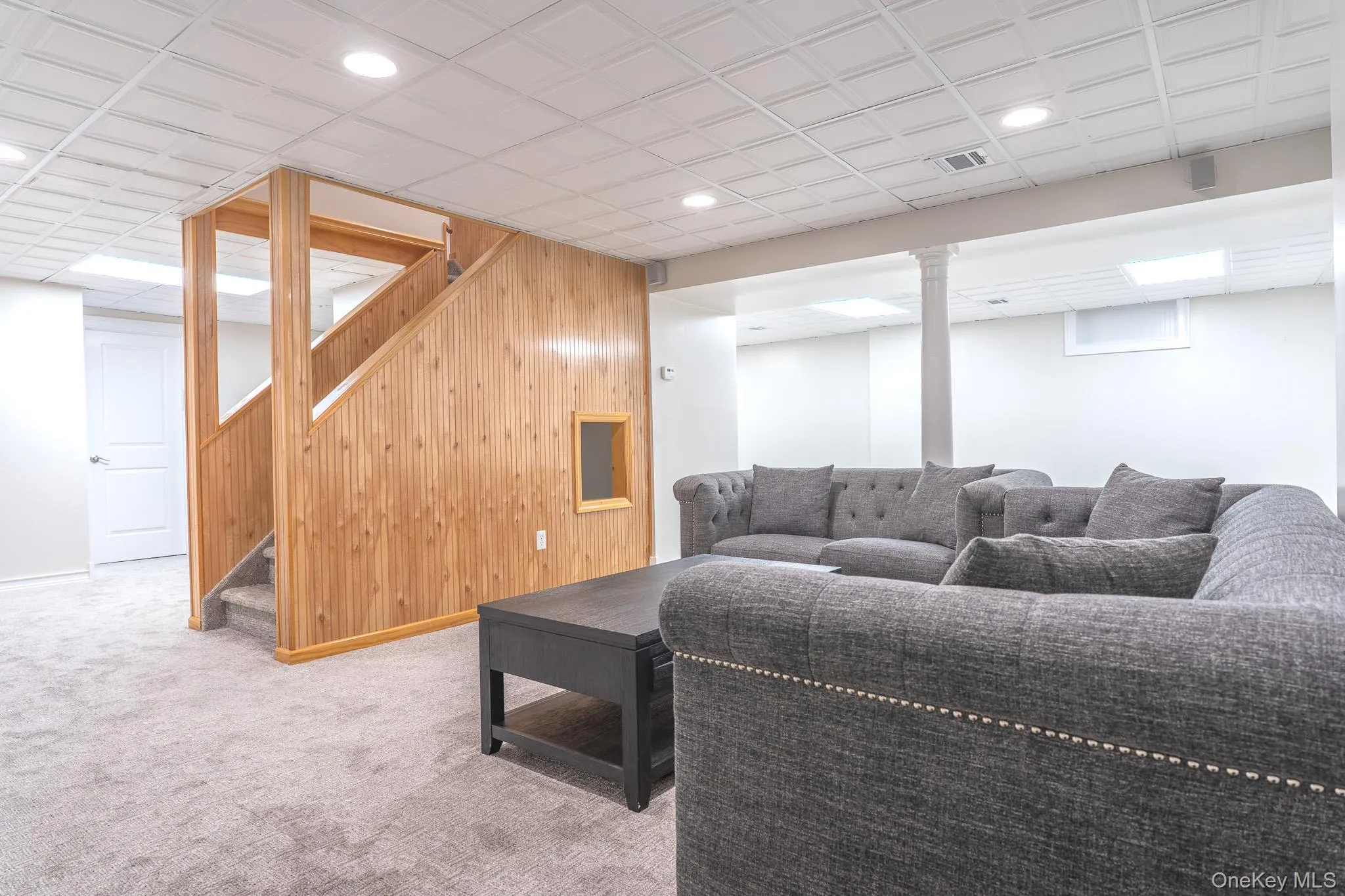 Finished lower level featuring a paneled wood staircase, recessed lighting, and light gray wall-to-wall carpeting Finished lower level featuring a paneled wood staircase, recessed lighting, and light gray wall-to-wall carpeting
