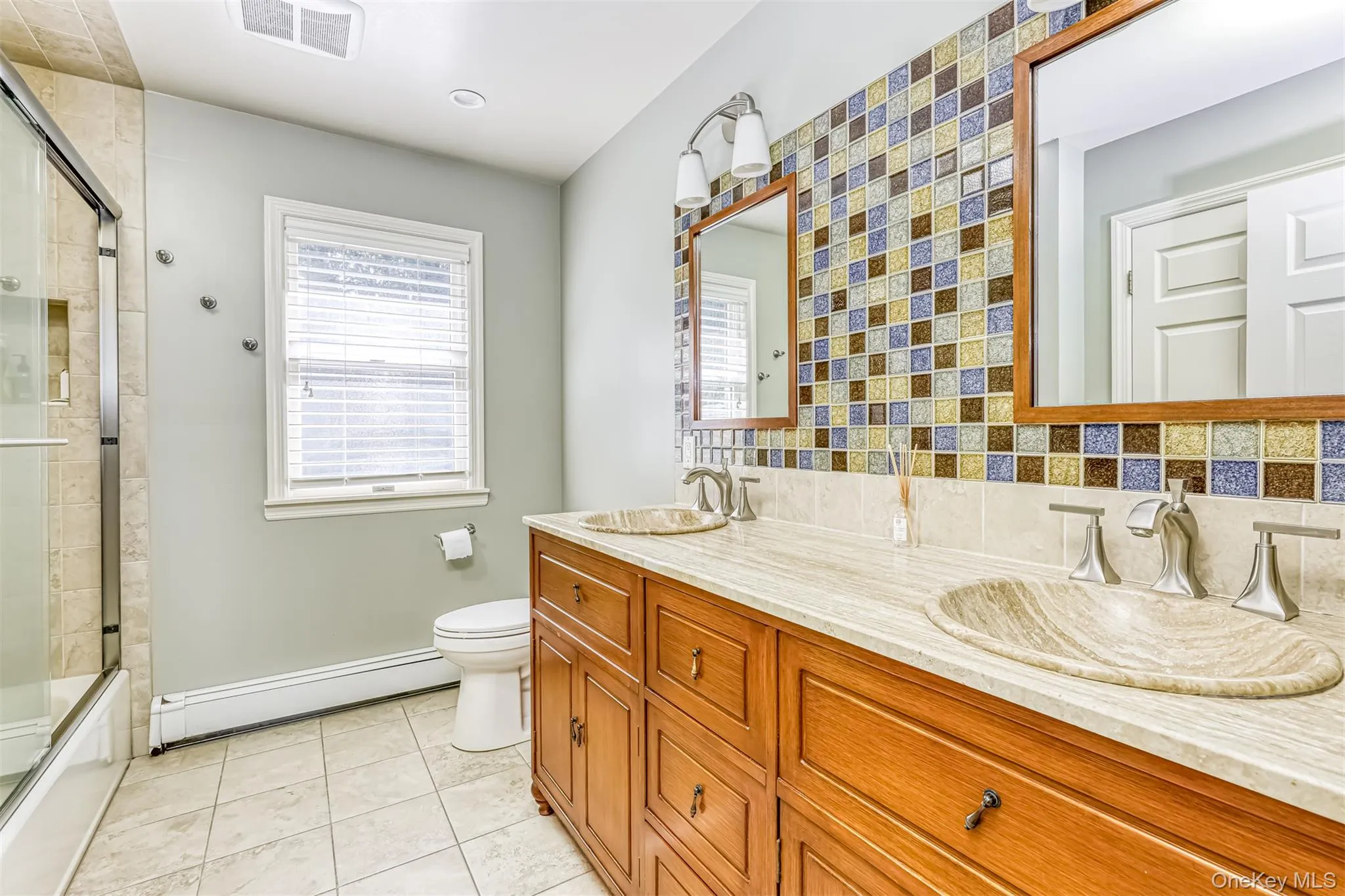 Spa-inspired master bath featuring dual vanities with marble countertops, custom wood cabinetry, and polished nickel fixtures Spa-inspired master bath featuring dual vanities with marble countertops, custom wood cabinetry, and polished nickel fixtures