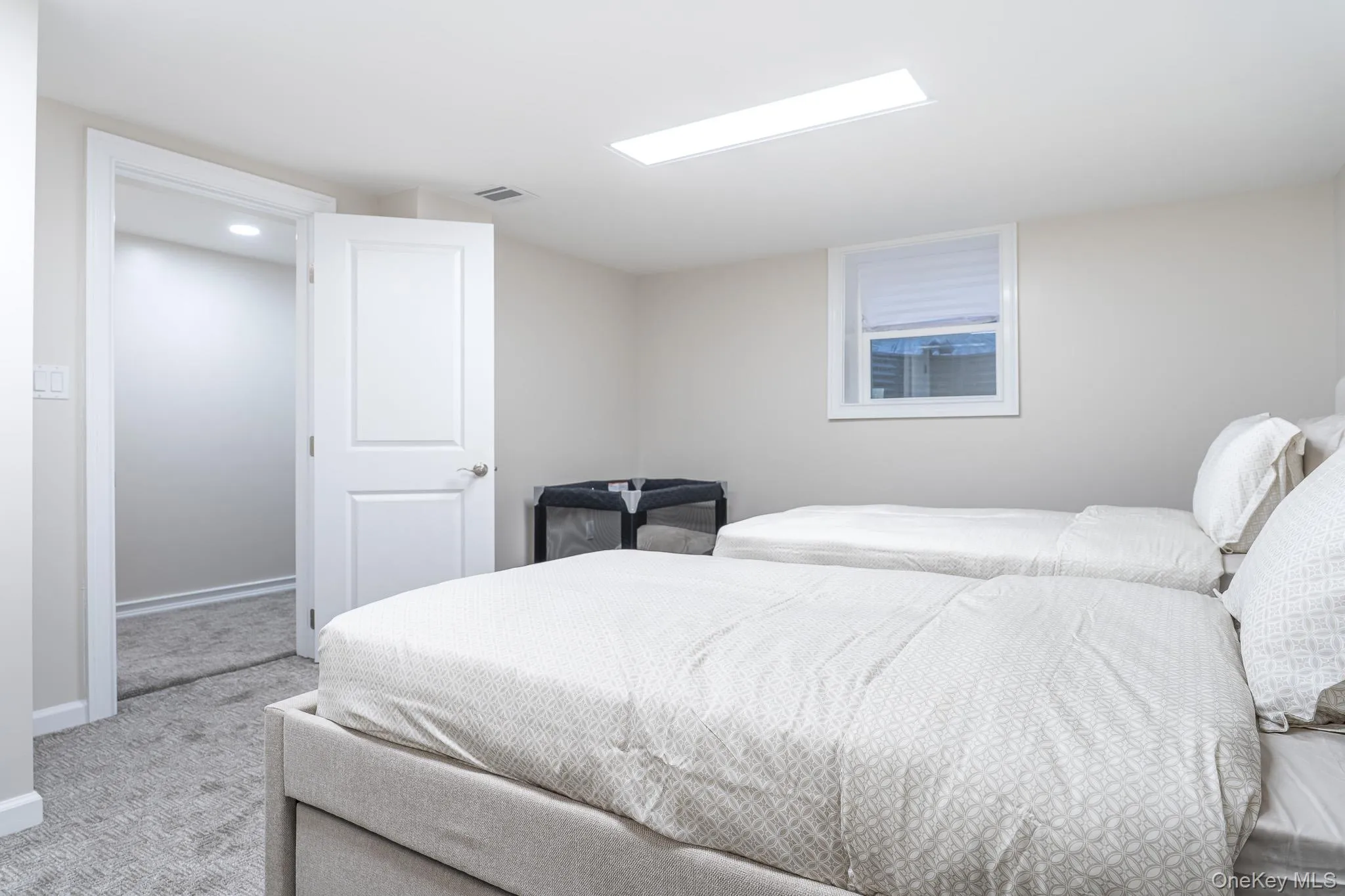 Bright, light-filled bedroom featuring two queen beds with crisp white bedding, recessed ceiling lighting, carpet flooring, and a large window with natural light Bright, light-filled bedroom featuring two queen beds with crisp white bedding, recessed ceiling lighting, carpet flooring, and a large window with natural light