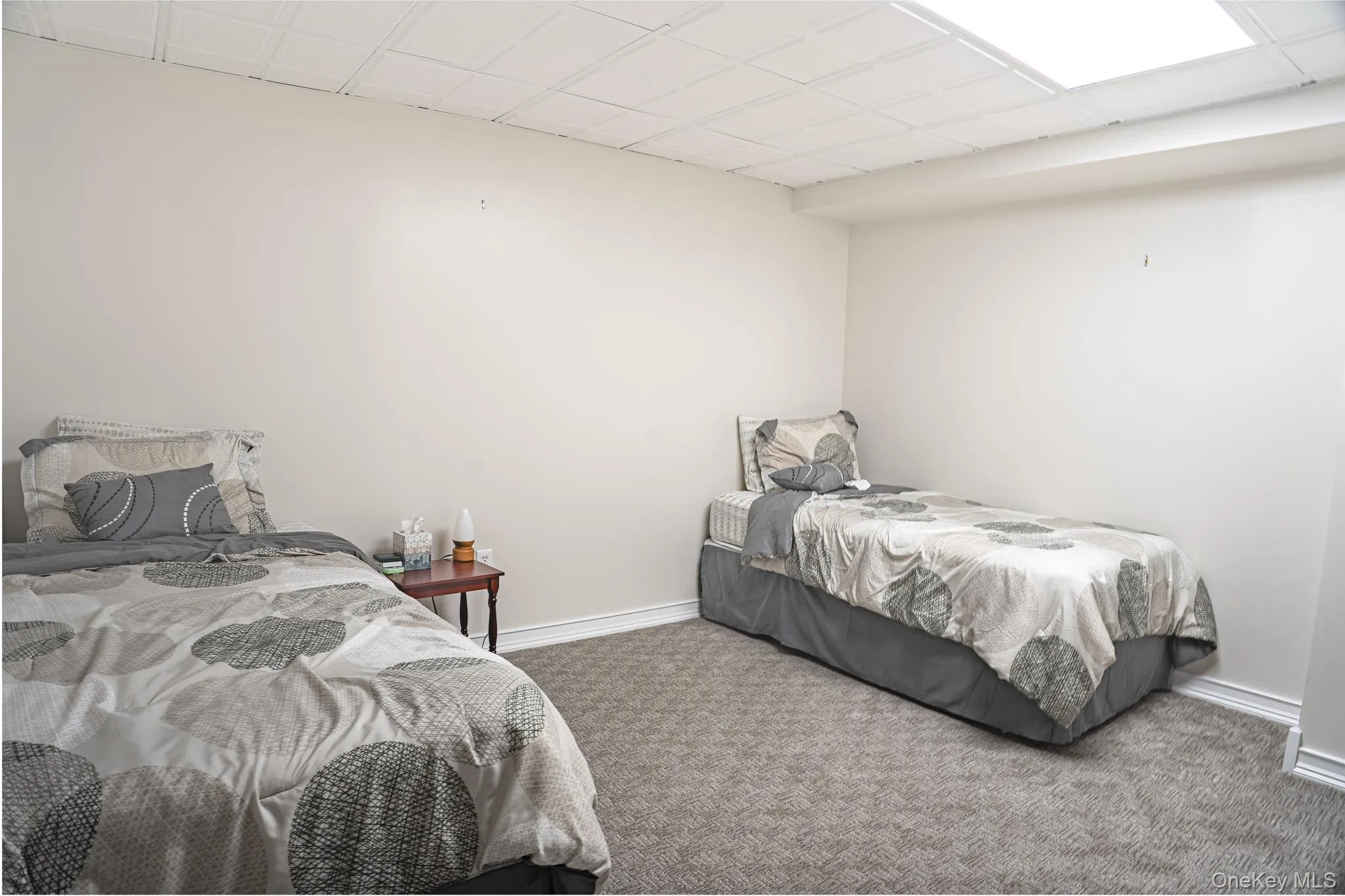 Comfortable bedroom featuring two twin beds with coordinating bedding, carpeted flooring, recessed ceiling lighting, and neutral wall finishes Comfortable bedroom featuring two twin beds with coordinating bedding, carpeted flooring, recessed ceiling lighting, and neutral wall finishes