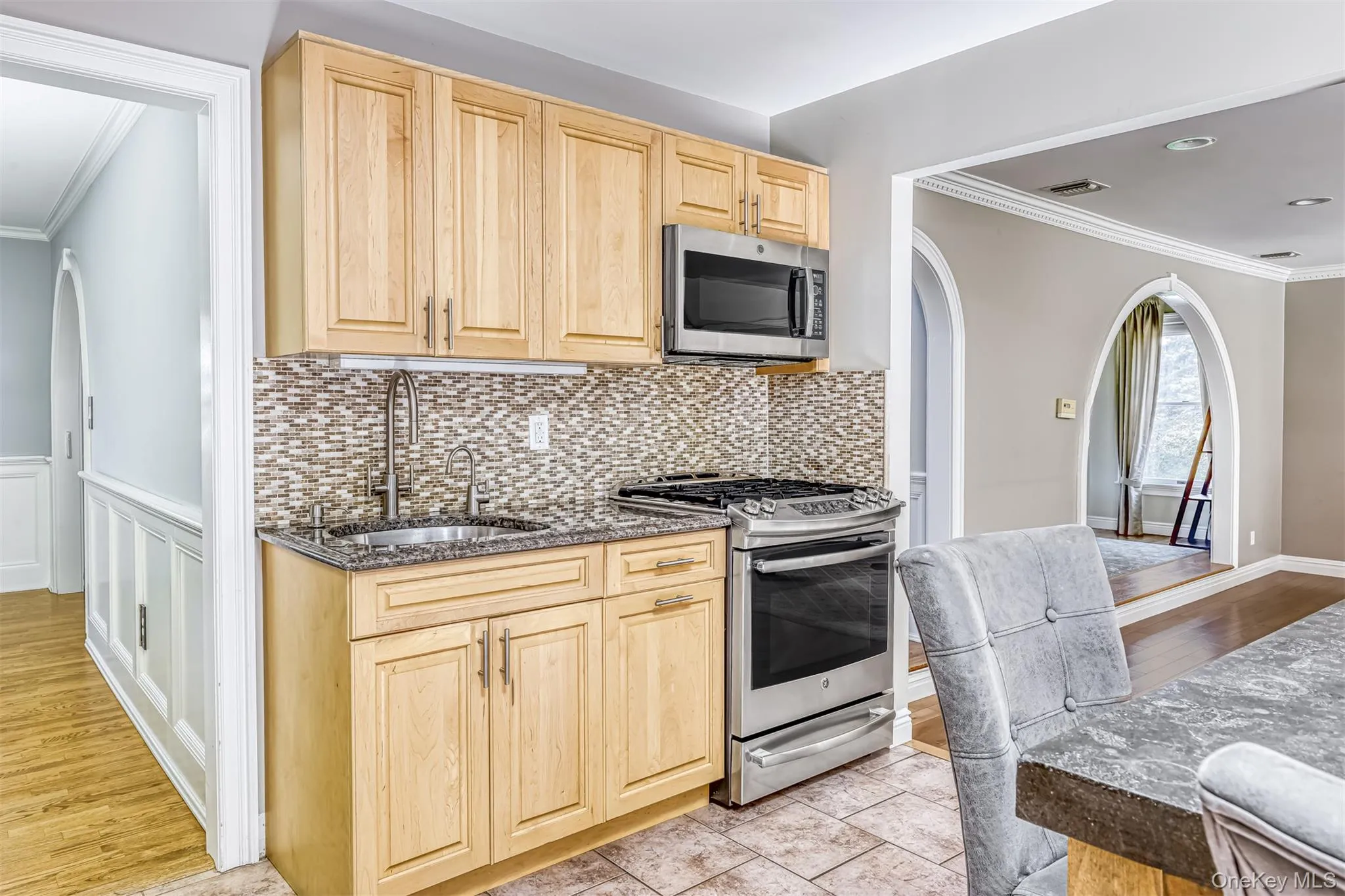 Kitchen area featuring light wood cabinetry, a mosaic tile backsplash, stainless steel appliances, and granite countertops Kitchen area featuring light wood cabinetry, a mosaic tile backsplash, stainless steel appliances, and granite countertops