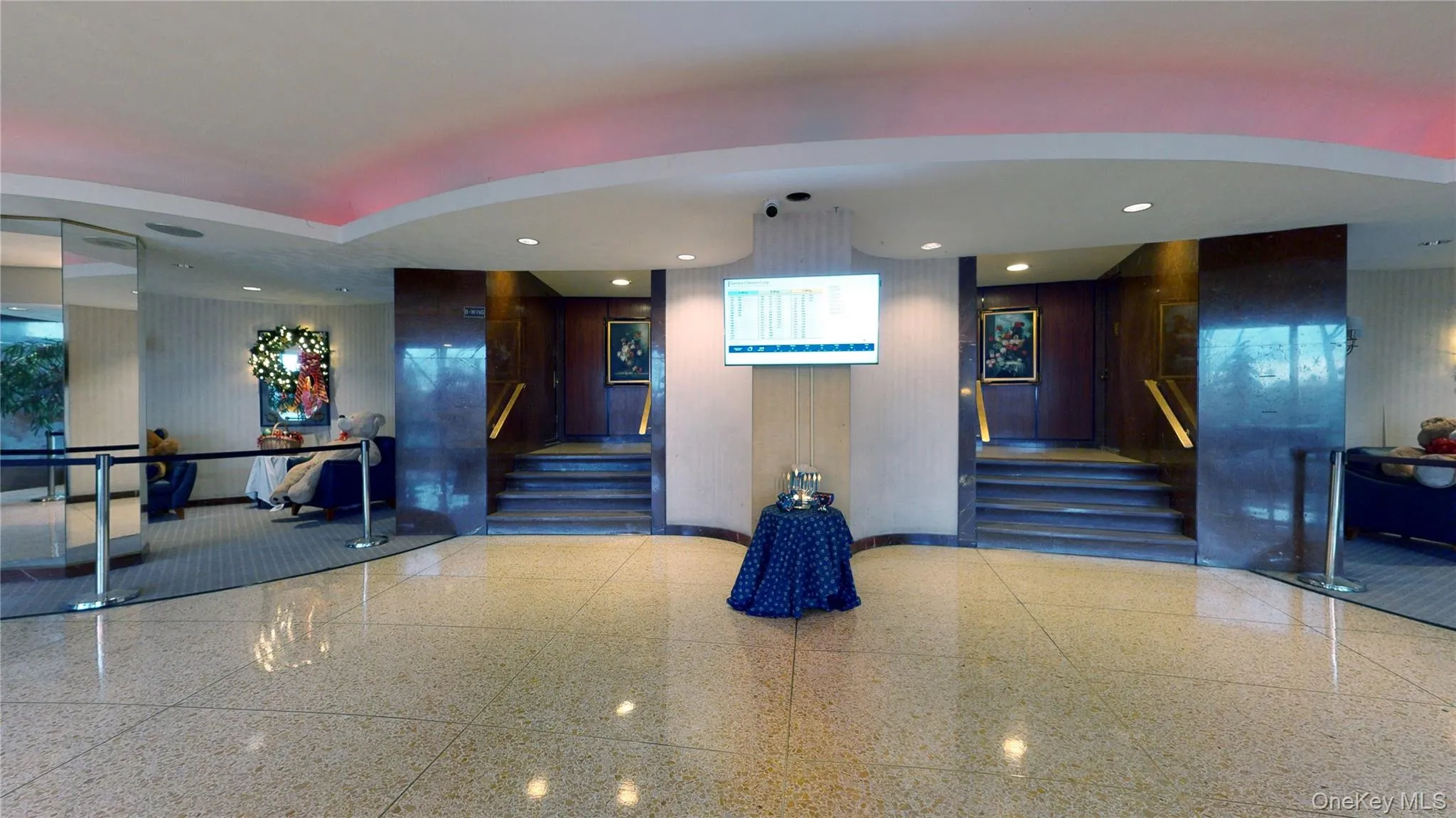 Spacious foyer featuring polished aggregate flooring, recessed lighting, and dual staircases with brass handrails Spacious foyer featuring polished aggregate flooring, recessed lighting, and dual staircases with brass handrails