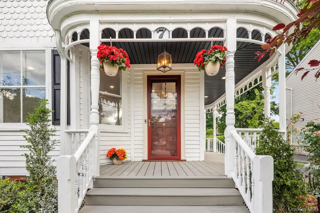 Welcoming front porch featuring a dark wood entry door with glass panel, recessed lighting, and a detailed balustrade Welcoming front porch featuring a dark wood entry door with glass panel, recessed lighting, and a detailed balustrade