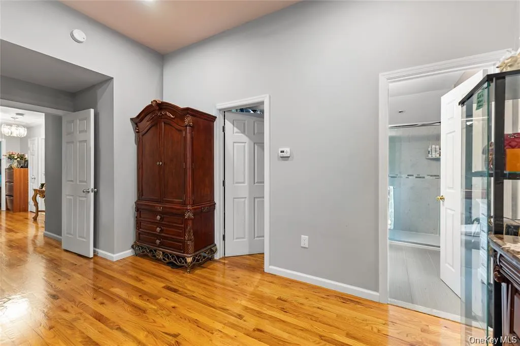 Rich wood-finish flooring extending through an open doorway, with light gray walls and white trim Rich wood-finish flooring extending through an open doorway, with light gray walls and white trim