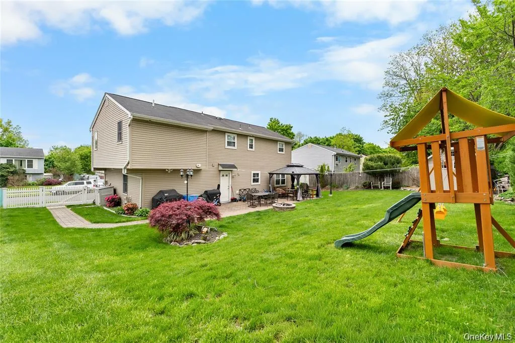 Expansive backyard featuring a green lawn, paved patio area, and mature perimeter trees Expansive backyard featuring a green lawn, paved patio area, and mature perimeter trees