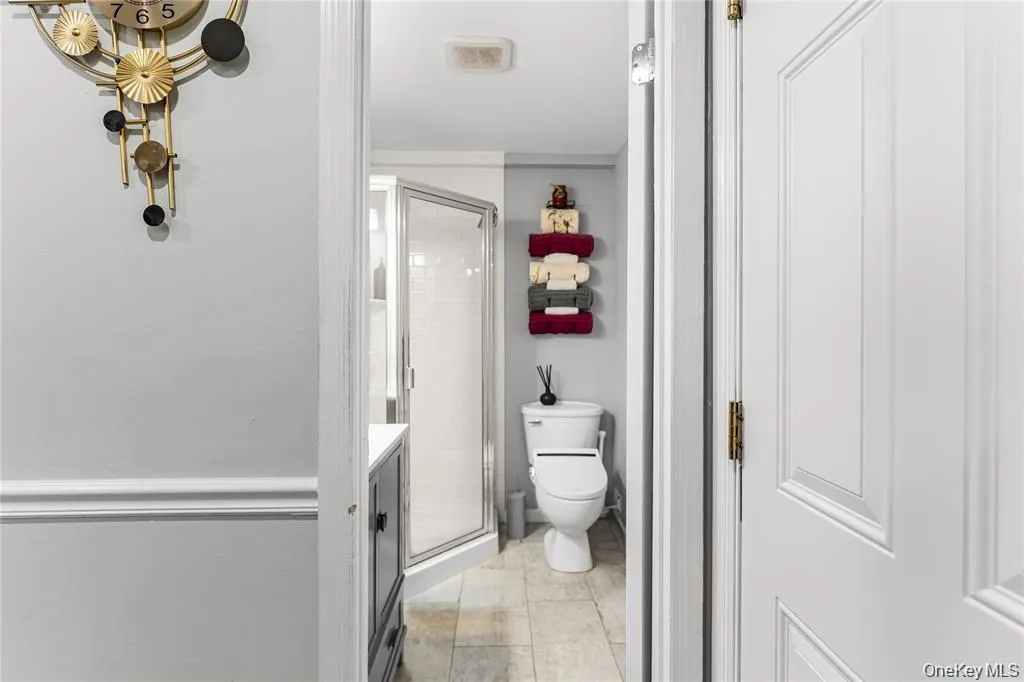 Three-quarter bathroom featuring a glass-enclosed shower, a vanity with a white countertop, and tiled flooring Three-quarter bathroom featuring a glass-enclosed shower, a vanity with a white countertop, and tiled flooring