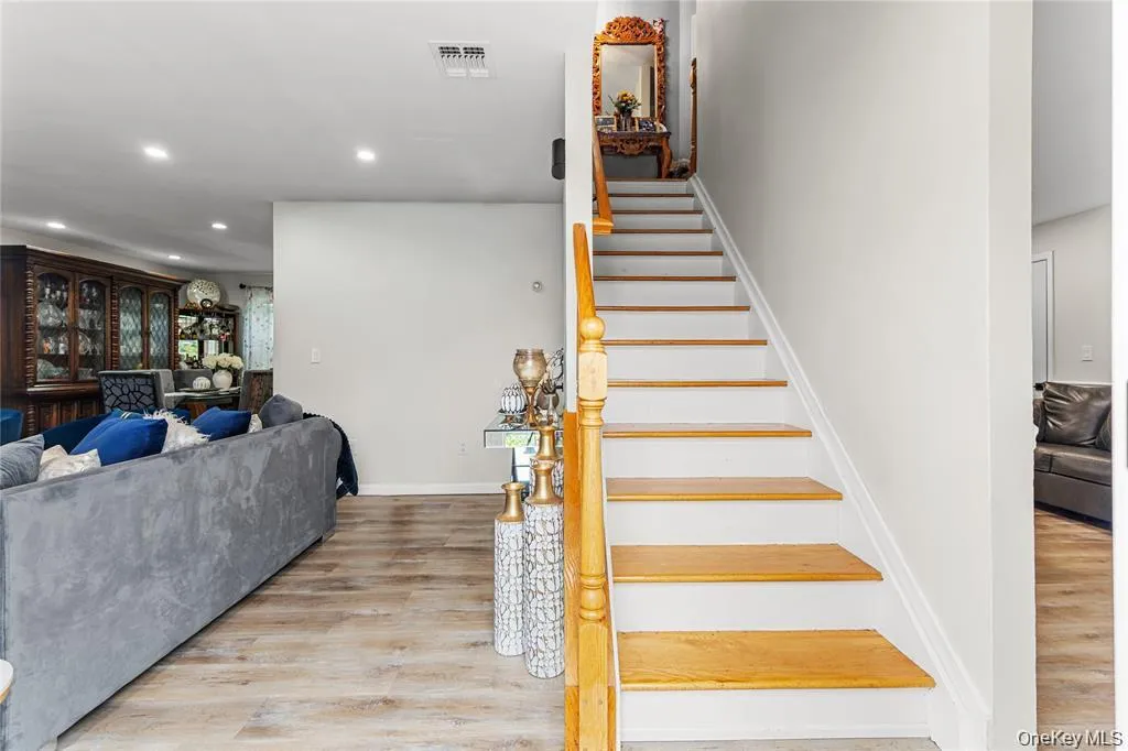 Staircase featuring wood treads and white risers with a wood handrail Staircase featuring wood treads and white risers with a wood handrail