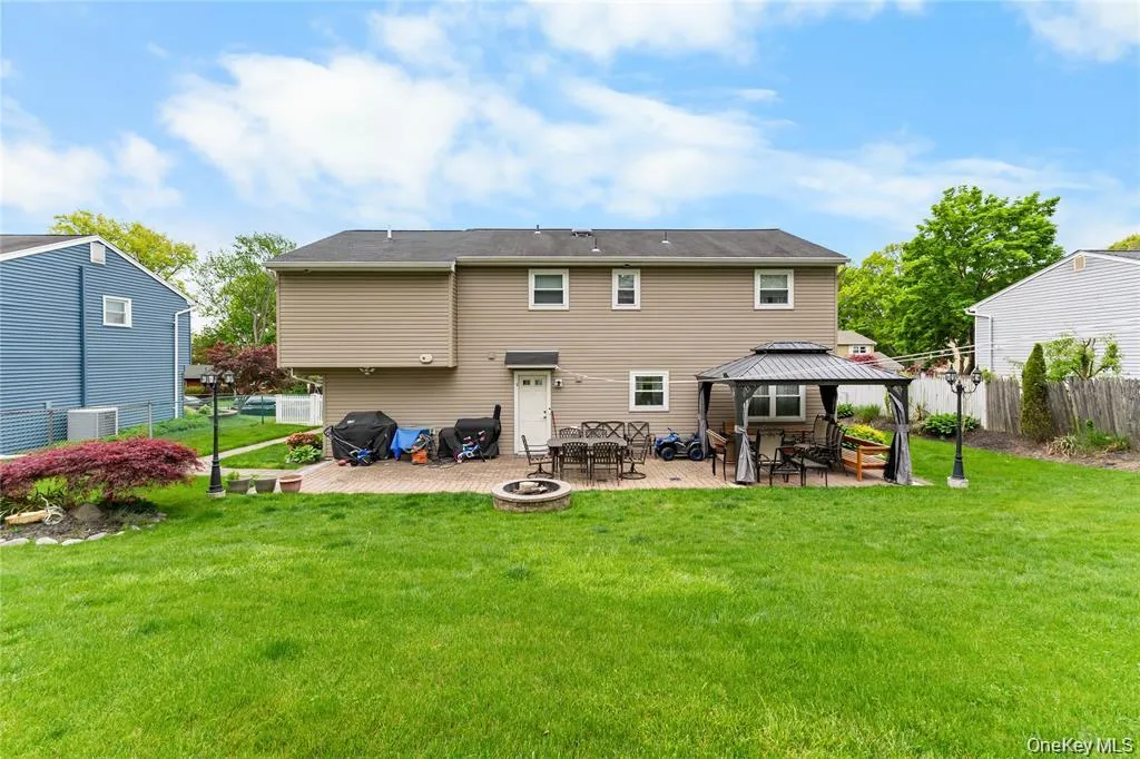 Expansive rear yard featuring a large green lawn and a paver patio Expansive rear yard featuring a large green lawn and a paver patio