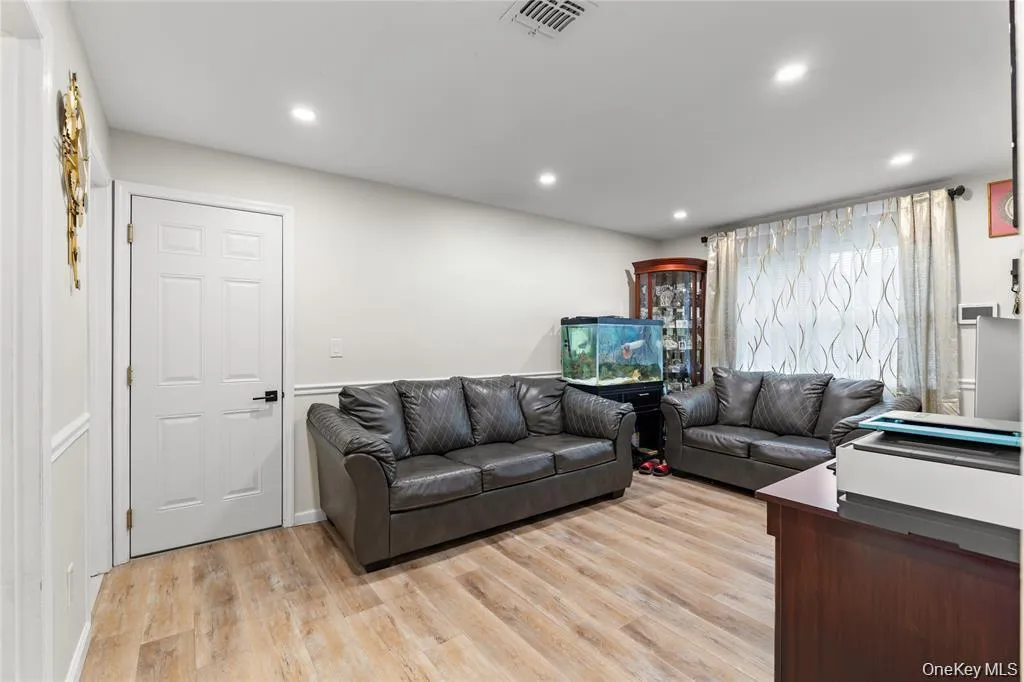 Spacious room featuring wood-finish flooring, recessed lighting, white trim, a multi-pane window, and a paneled white door with dark hardware Spacious room featuring wood-finish flooring, recessed lighting, white trim, a multi-pane window, and a paneled white door with dark hardware