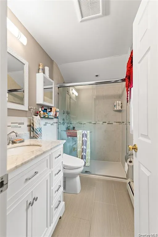 Bathroom featuring a glass-enclosed shower, a white vanity with a light-colored countertop, and a contemporary toilet Bathroom featuring a glass-enclosed shower, a white vanity with a light-colored countertop, and a contemporary toilet