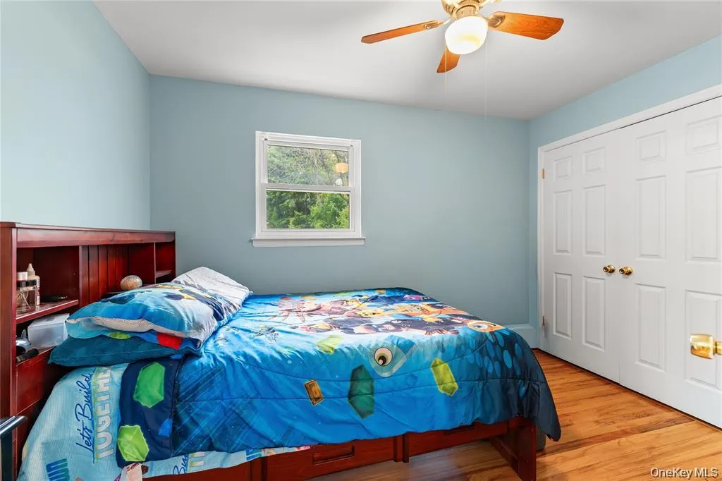Room featuring wood-finish flooring, light blue walls, and a white trim window Room featuring wood-finish flooring, light blue walls, and a white trim window