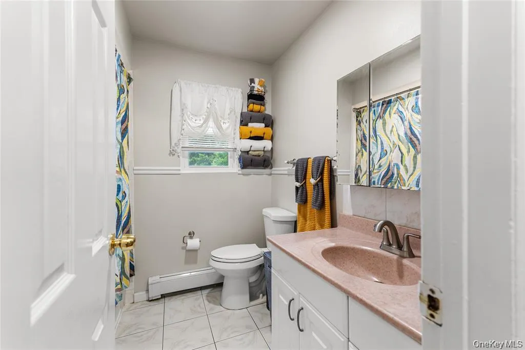 Bathroom featuring a vanity with a reddish countertop, built-in medicine cabinet, white tile flooring, and a window Bathroom featuring a vanity with a reddish countertop, built-in medicine cabinet, white tile flooring, and a window