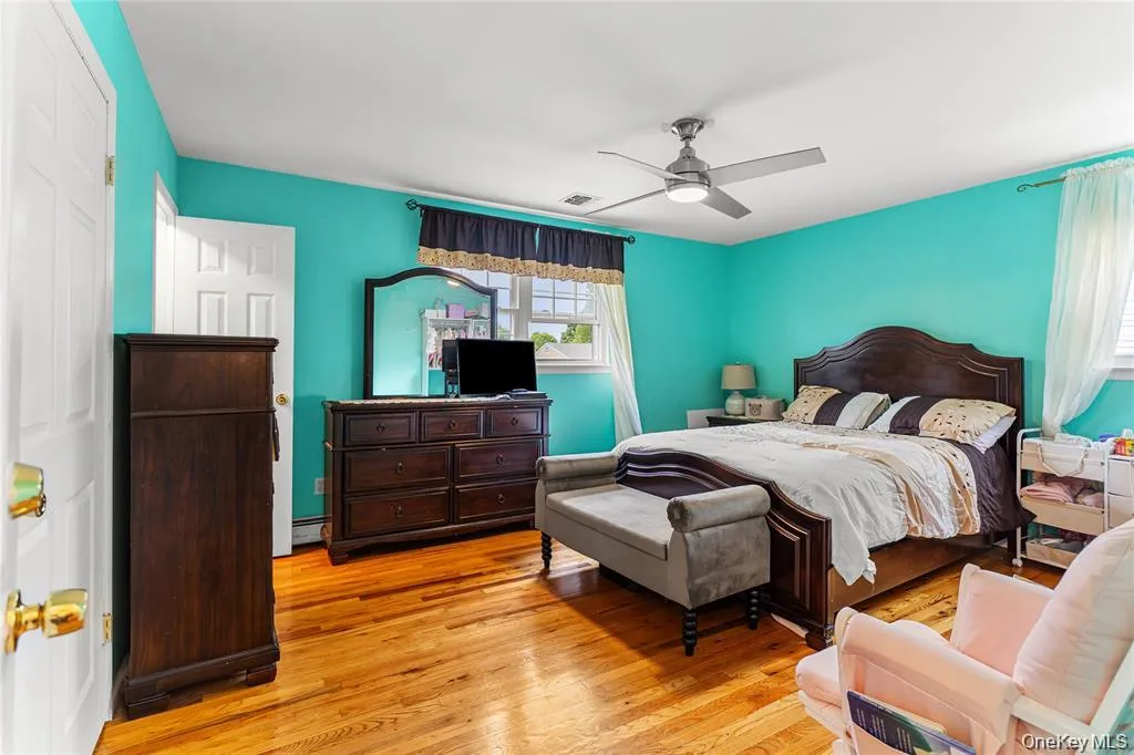 Hardwood flooring throughout this bright room, featuring a contemporary ceiling fan, baseboard molding, and multiple windows with natural light Hardwood flooring throughout this bright room, featuring a contemporary ceiling fan, baseboard molding, and multiple windows with natural light