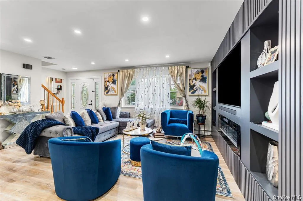 Open-concept living space featuring wood-finish flooring, recessed lighting, and a custom built-in entertainment center with integrated shelving Open-concept living space featuring wood-finish flooring, recessed lighting, and a custom built-in entertainment center with integrated shelving