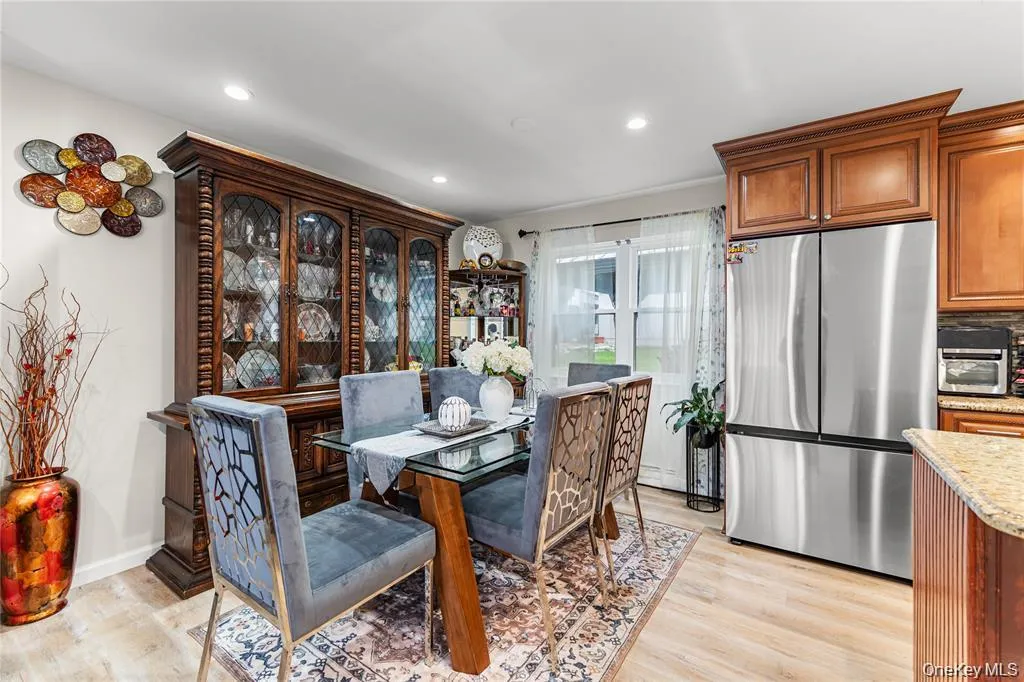 Dining area featuring wood-finish flooring, recessed lighting, and a window with white sheer curtains Dining area featuring wood-finish flooring, recessed lighting, and a window with white sheer curtains