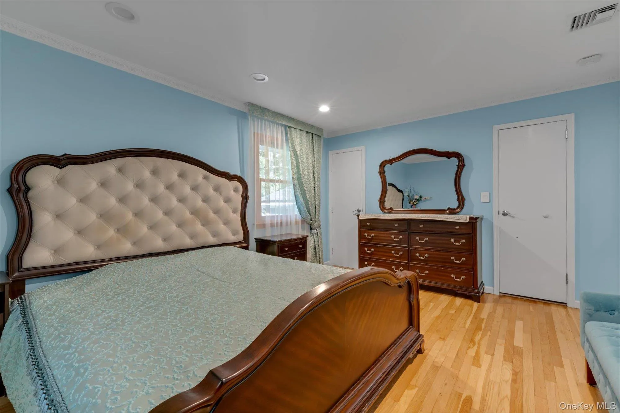 Primary bedroom Hardwood flooring, recessed ceiling lighting, crown molding, and multiple windows Primary bedroom Hardwood flooring, recessed ceiling lighting, crown molding, and multiple windows