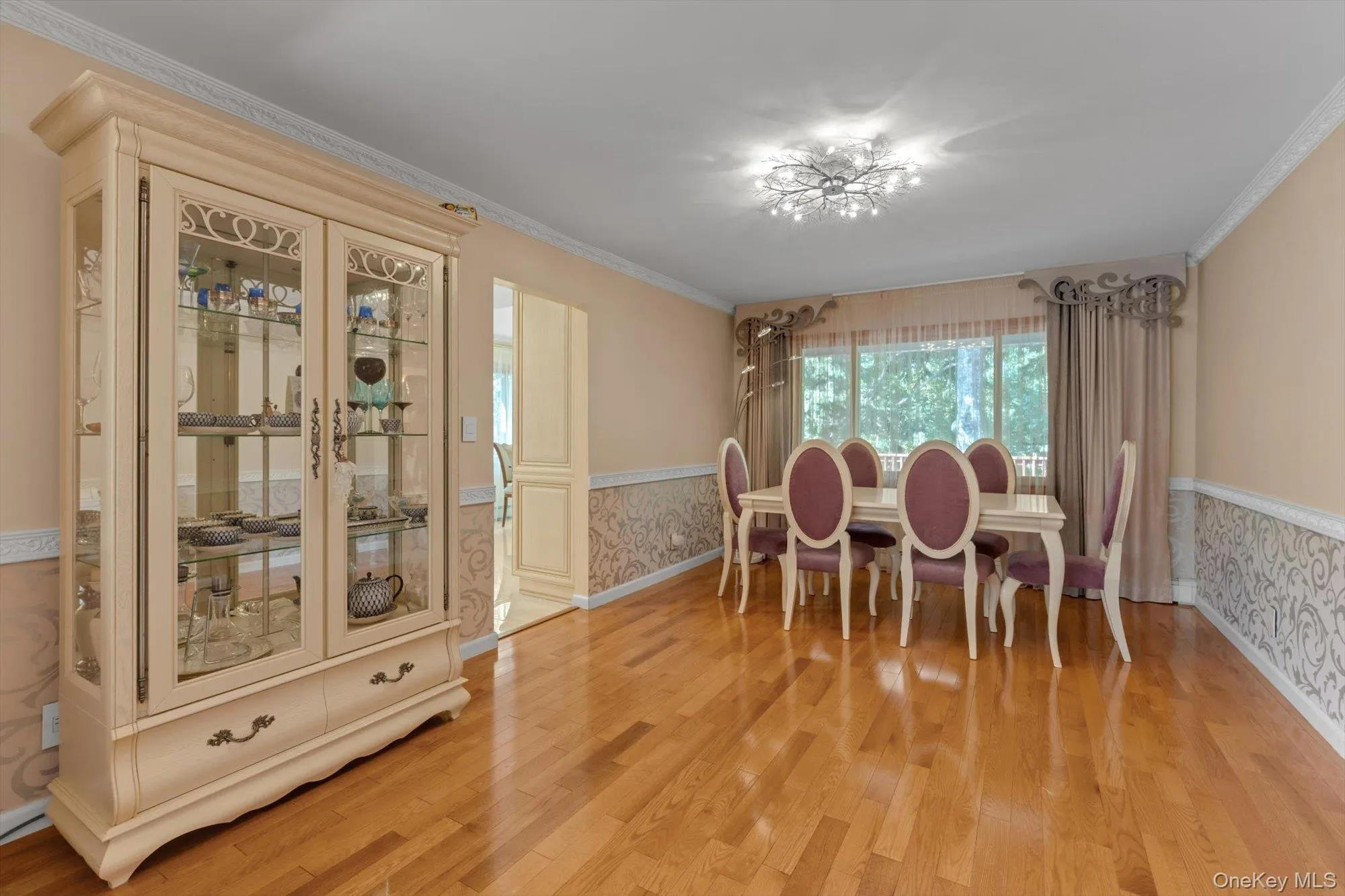 Hardwood flooring, decorative wall paneling, crown molding, large window, and ceiling-mounted light fixture Hardwood flooring, decorative wall paneling, crown molding, large window, and ceiling-mounted light fixture