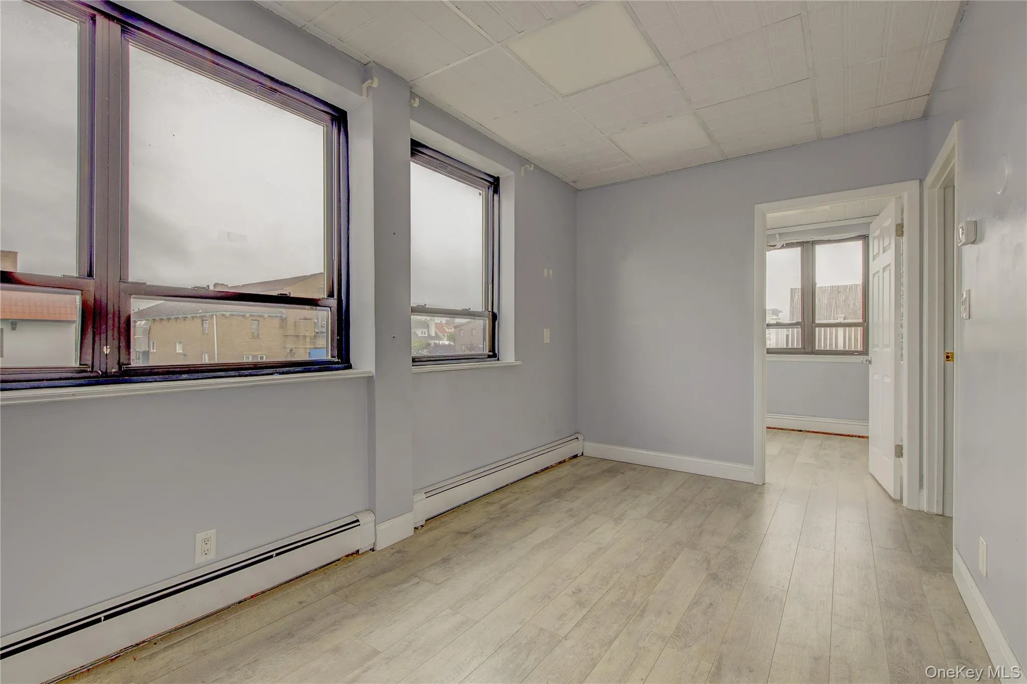 Empty room featuring a baseboard radiator, wood finished floors, and baseboards Empty room featuring a baseboard radiator, wood finished floors, and baseboards