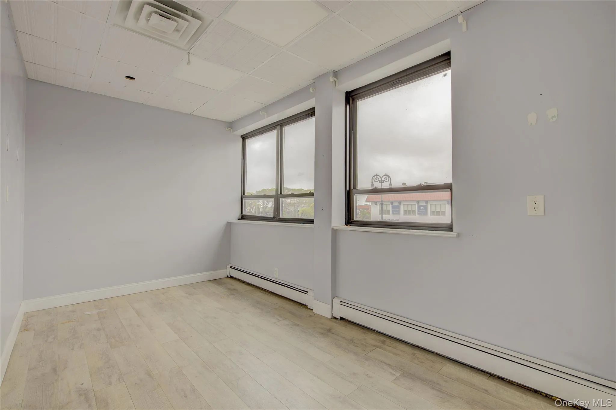 Spare room with baseboard heating, wood finished floors, and baseboards Spare room with baseboard heating, wood finished floors, and baseboards