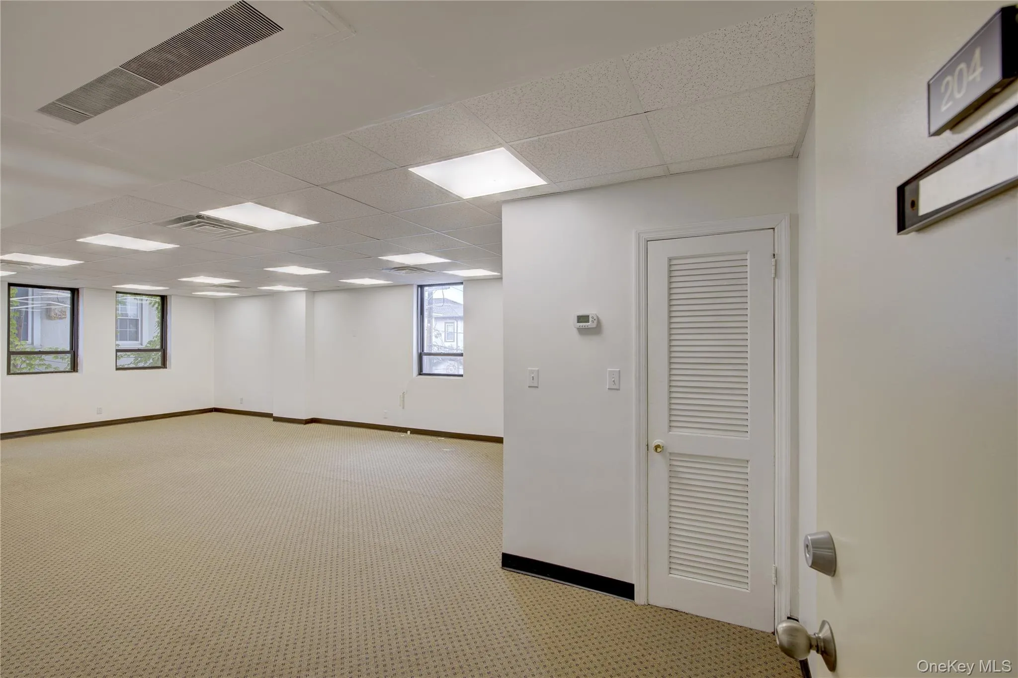 Spare room with a drop ceiling, light carpet, and baseboards Spare room with a drop ceiling, light carpet, and baseboards