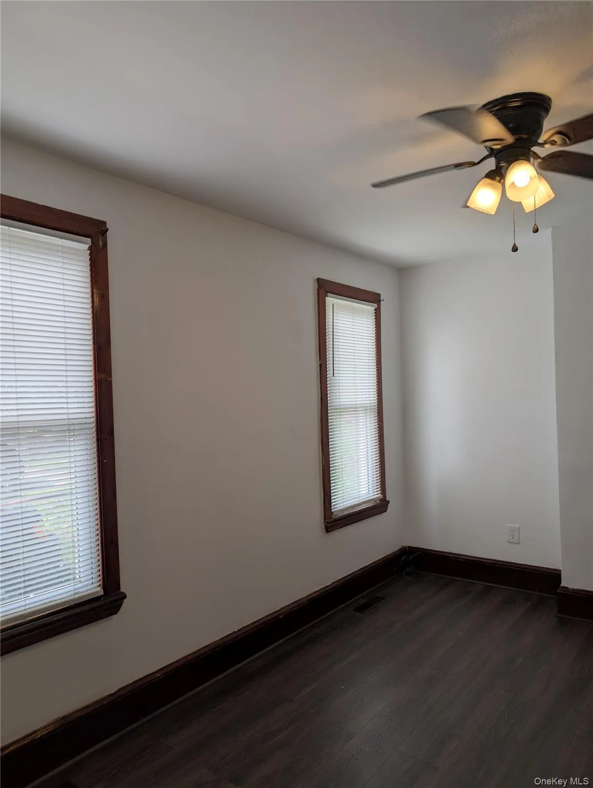 Bright dining room with expansive windows featuring wood-frame casings, vinyl wood-finish flooring, and ceiling-mounted fan with integrated lighting fixtures Bright dining room with expansive windows featuring wood-frame casings, vinyl wood-finish flooring, and ceiling-mounted fan with integrated lighting fixtures