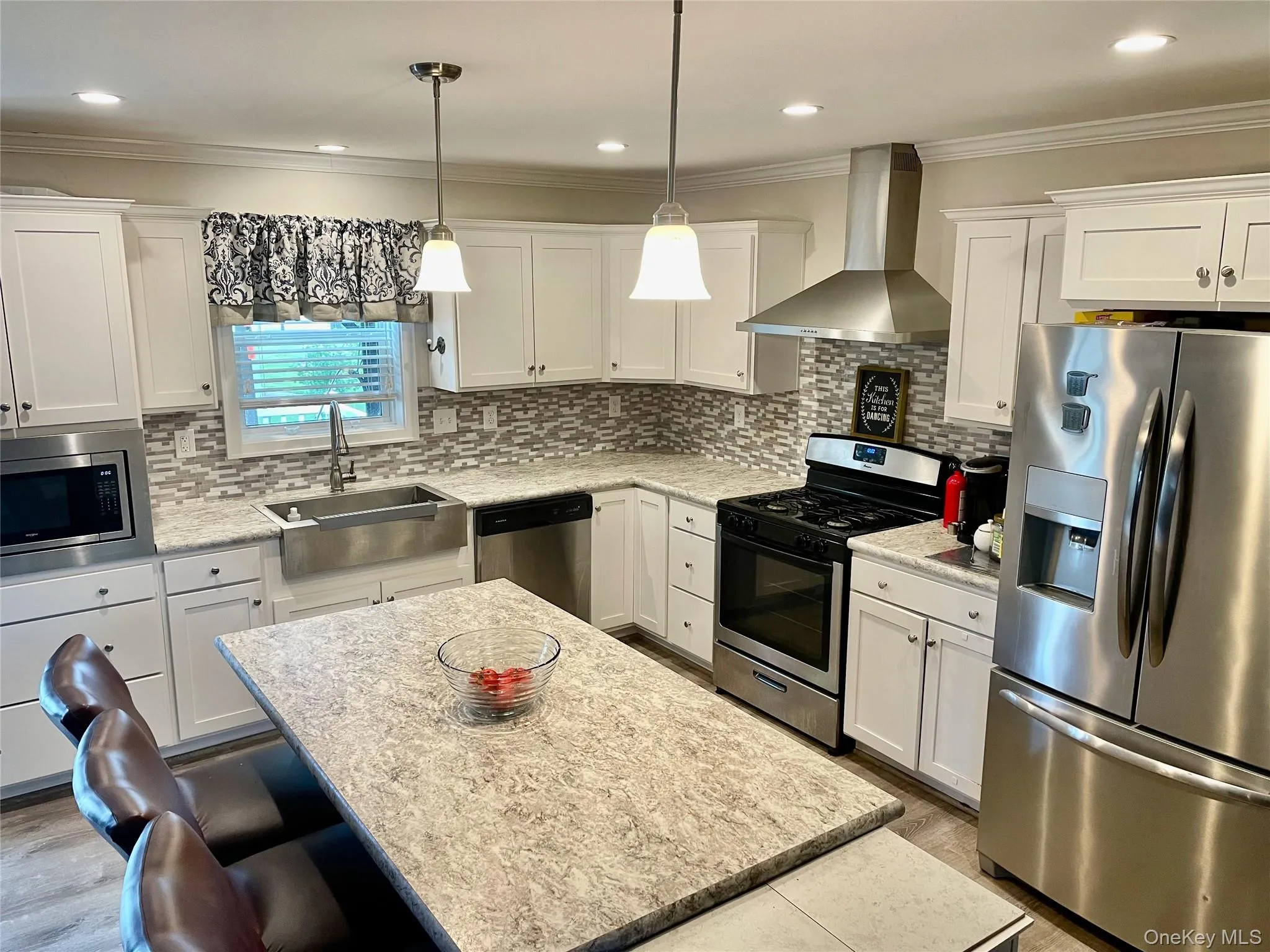 White cabinetry with ample storage, stainless steel appliances, stone-look countertops, and a full tile backsplash White cabinetry with ample storage, stainless steel appliances, stone-look countertops, and a full tile backsplash
