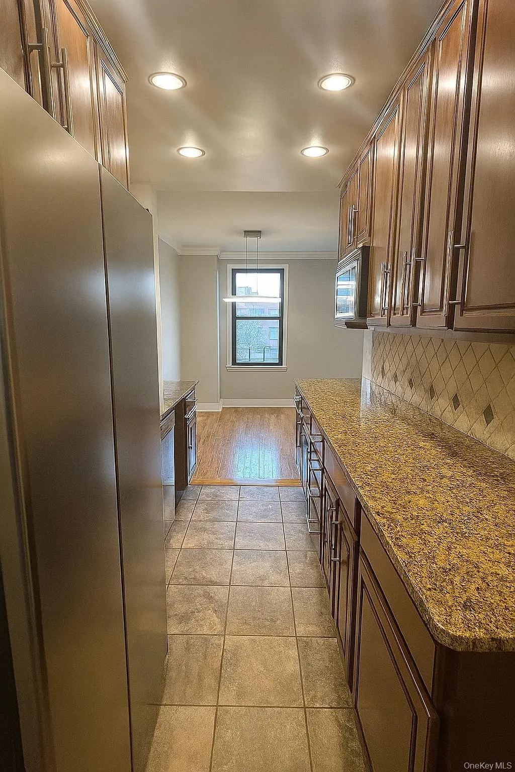 Galley kitchen with with stainless steel appliances,, decorative backsplash, recessed lighting, dark stone counters, and decorative light fixtures Galley kitchen with with stainless steel appliances,, decorative backsplash, recessed lighting, dark stone counters, and decorative light fixtures