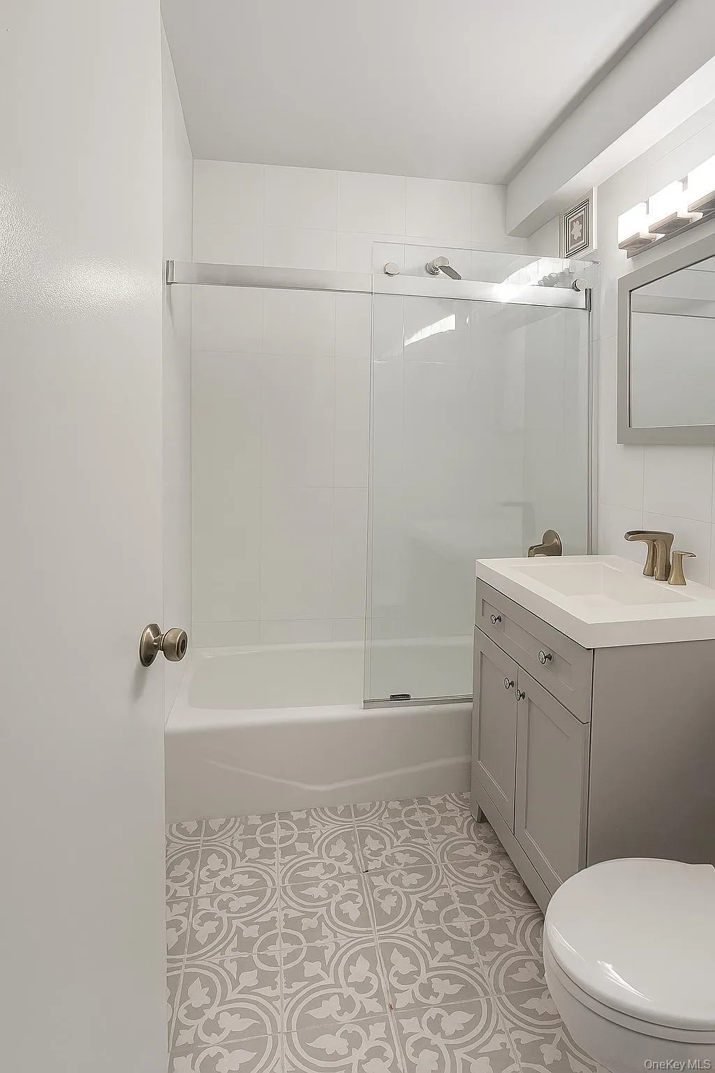 Updated hall full bath with vanity, enclosed tub / shower combo, and tile patterned floors Updated hall full bath with vanity, enclosed tub / shower combo, and tile patterned floors