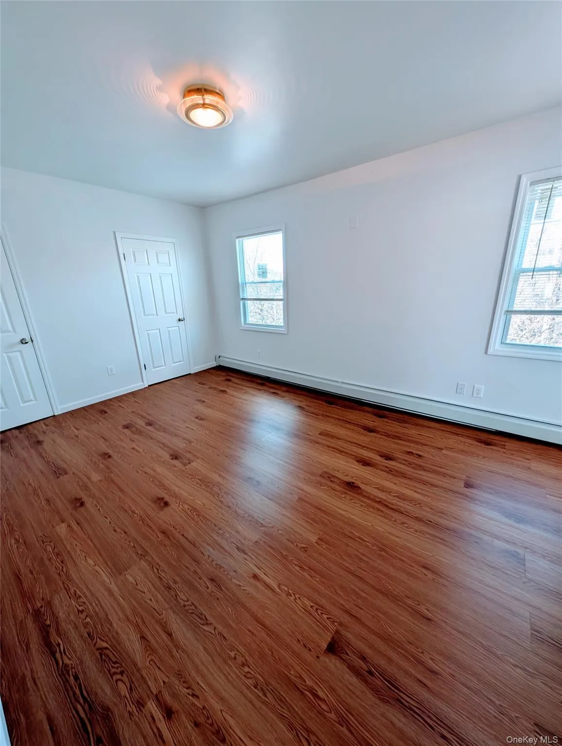 Unfurnished bedroom featuring a baseboard radiator, wood finished floors, and baseboards Unfurnished bedroom featuring a baseboard radiator, wood finished floors, and baseboards