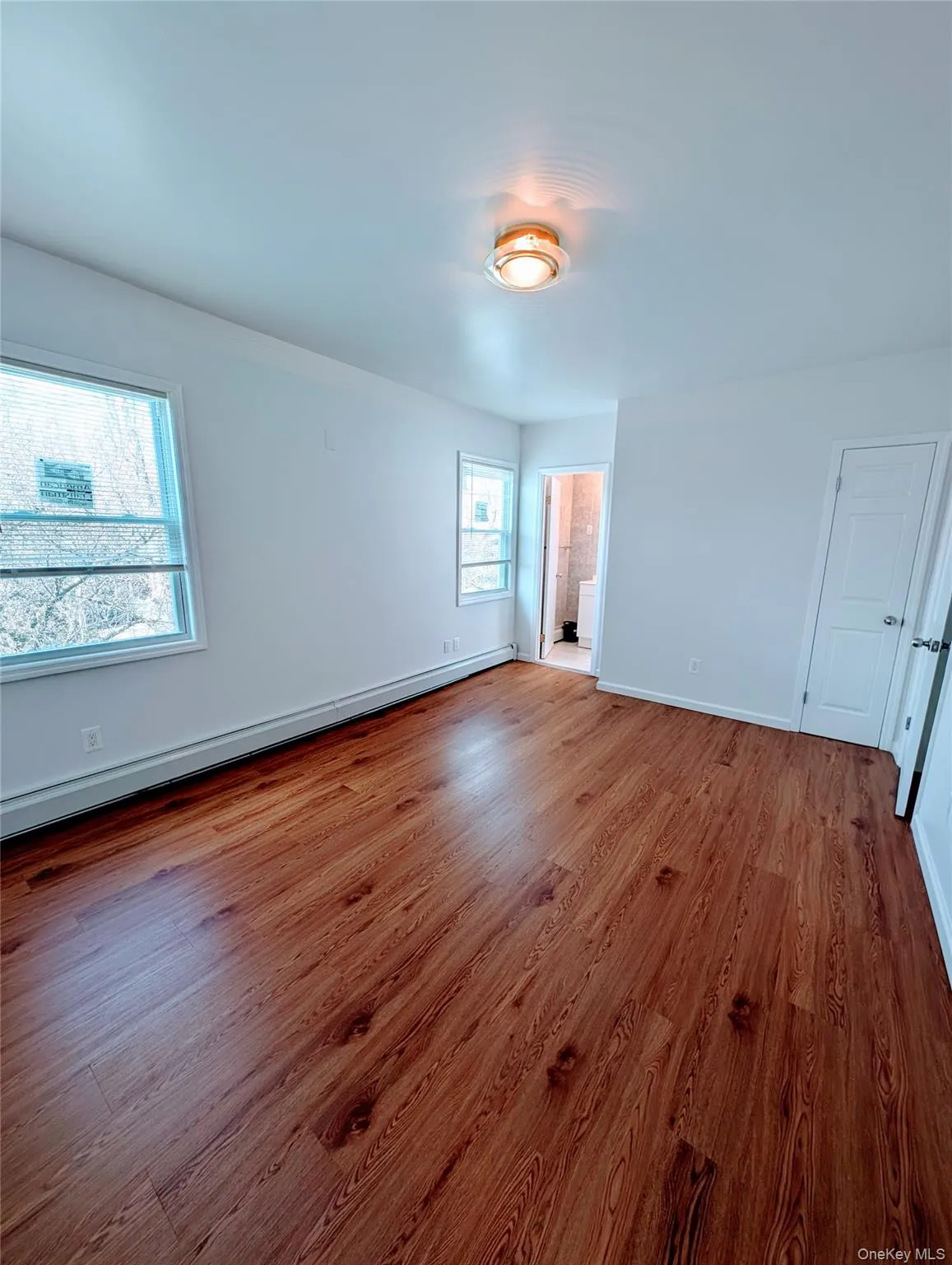 Empty room with a baseboard heating unit, baseboards, and wood finished floors Empty room with a baseboard heating unit, baseboards, and wood finished floors