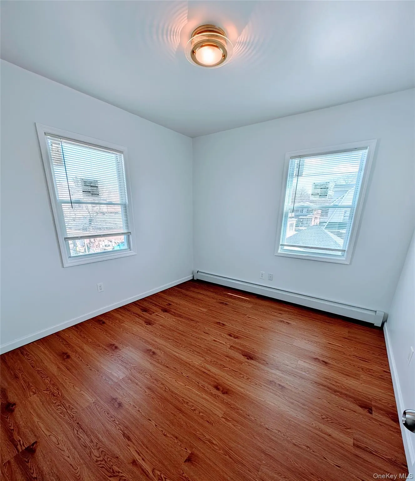 Spare room with baseboard heating, baseboards, and wood finished floors Spare room with baseboard heating, baseboards, and wood finished floors