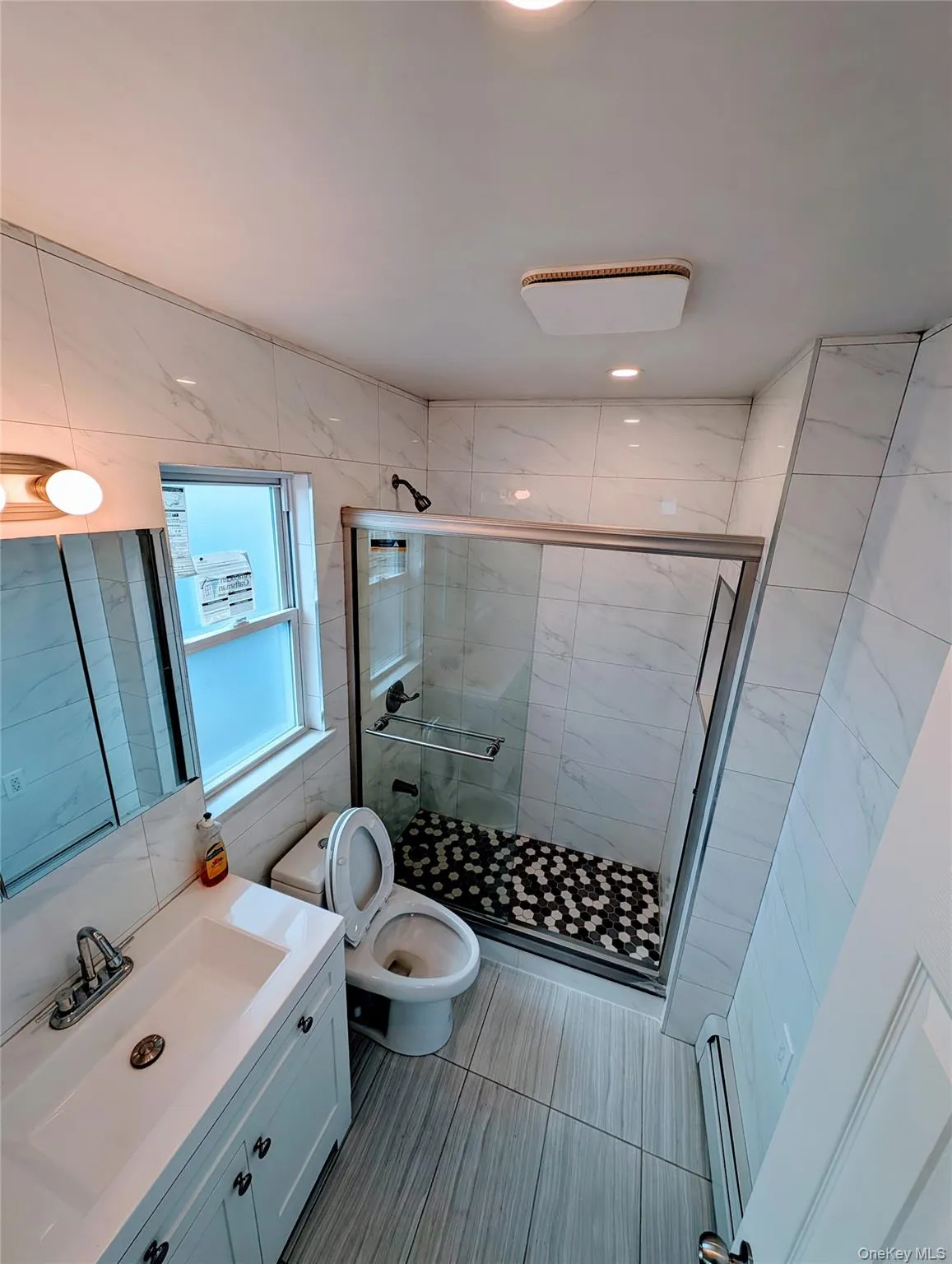 Bathroom with toilet, a stall shower, vanity, and tile walls Bathroom with toilet, a stall shower, vanity, and tile walls